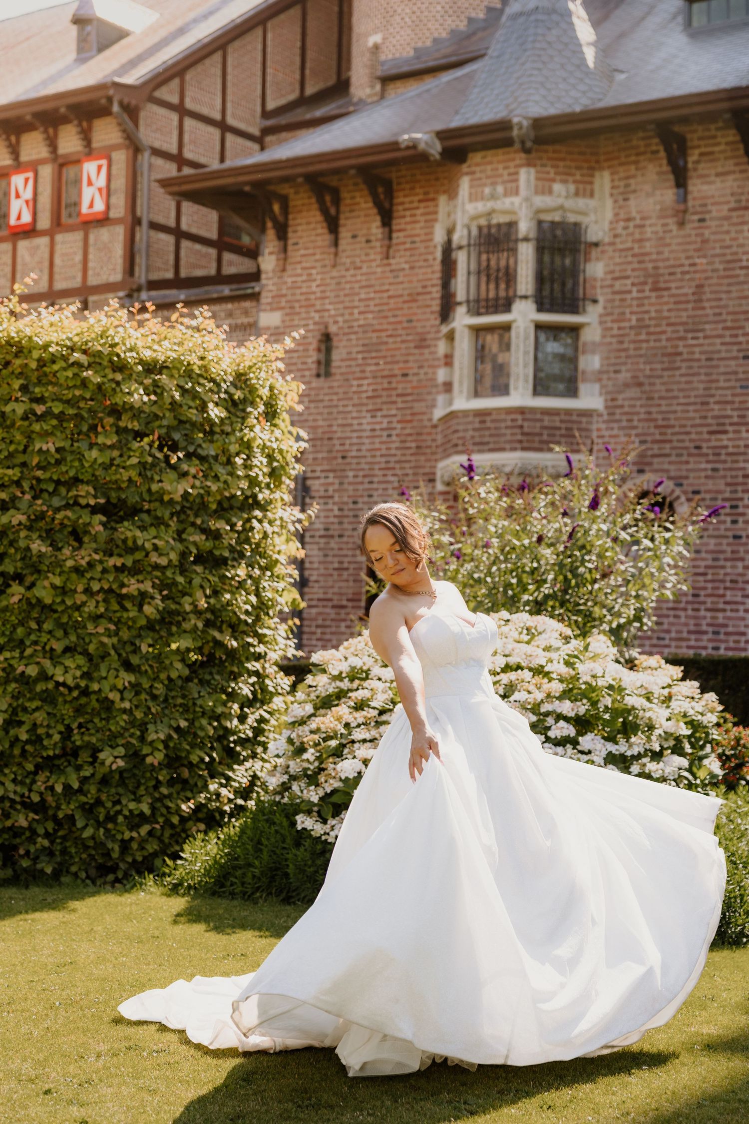 Een bruid swiert met haar jurk in de tuin van Kasteel de Haar in Utrecht