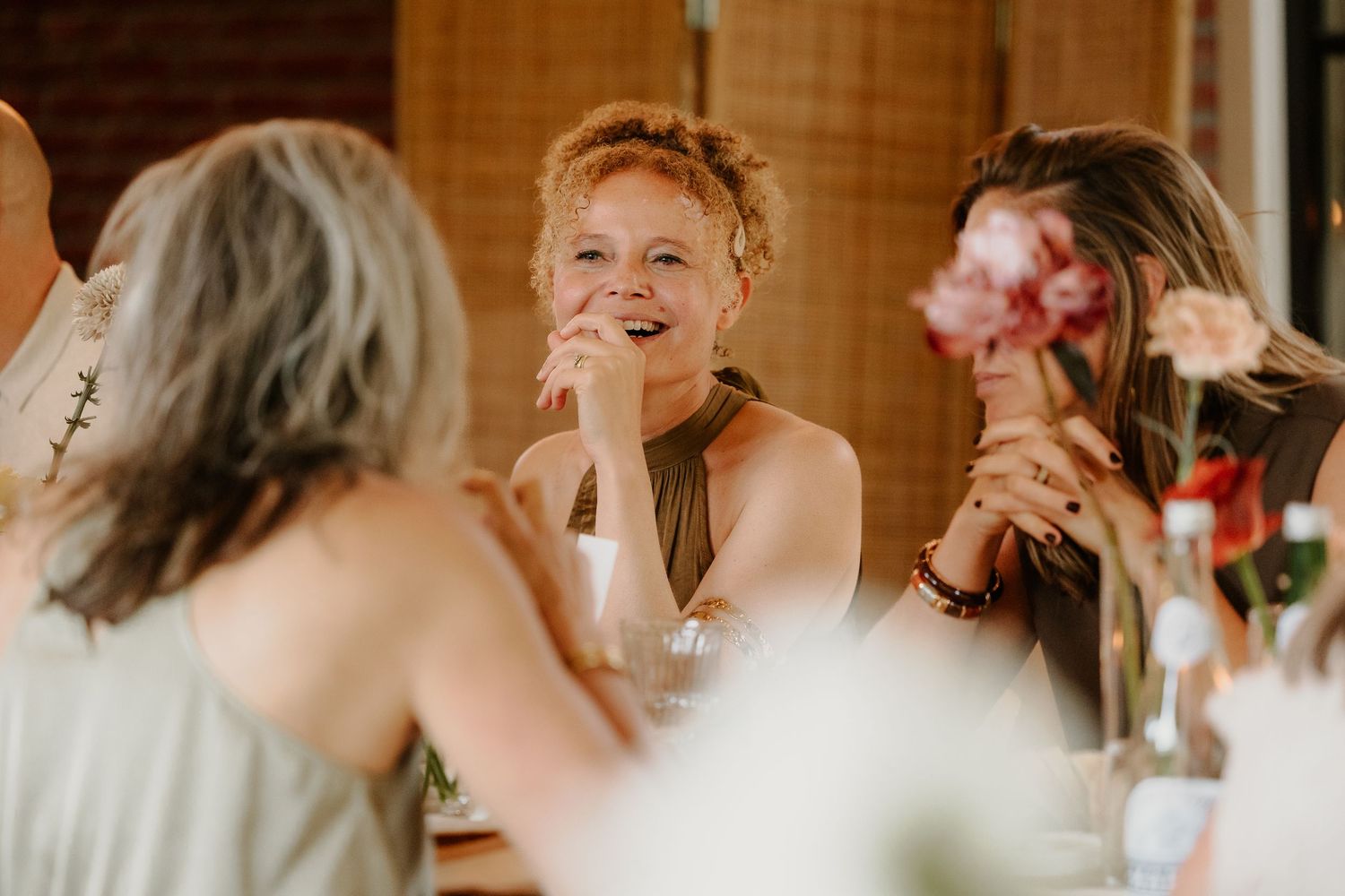 Lachende bruiloftsgasten tijdens een gezellig moment aan de dinertafel