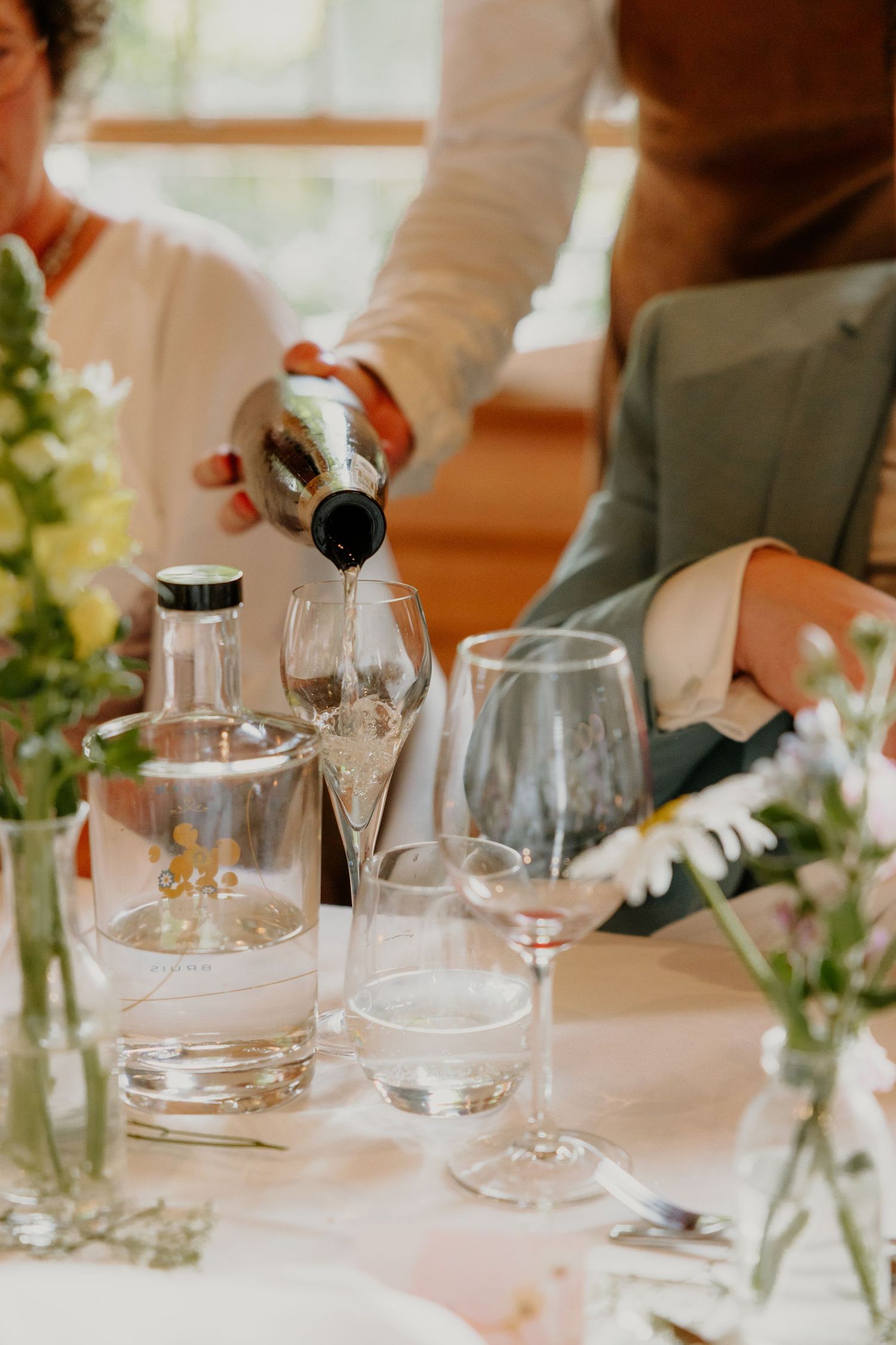 Wijn wordt ingeschonken aan een gedekte dinertafel tijdens de bruiloft
