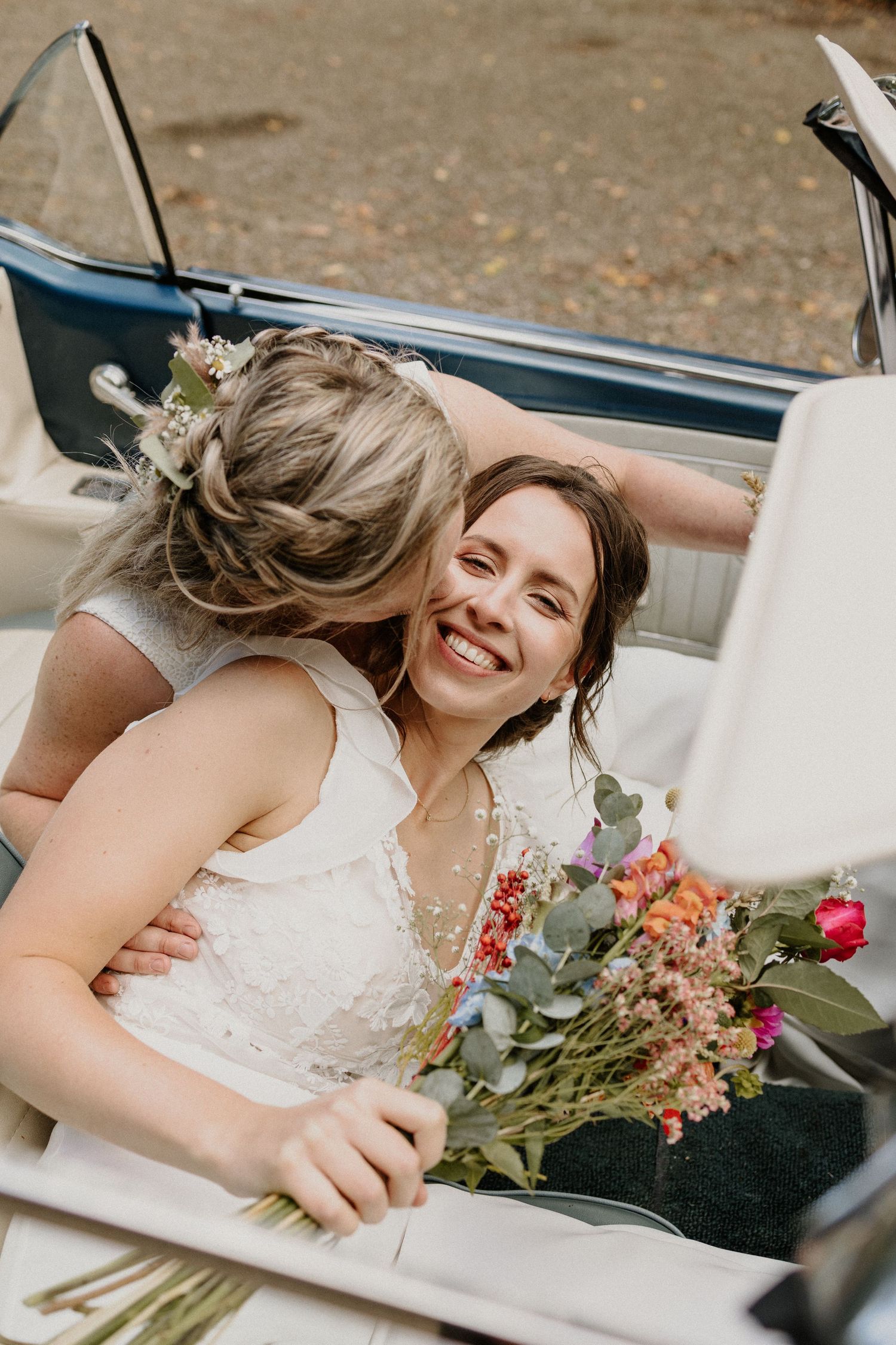 Twee bruiden samen in een klassieke auto tijdens hun trouwdag