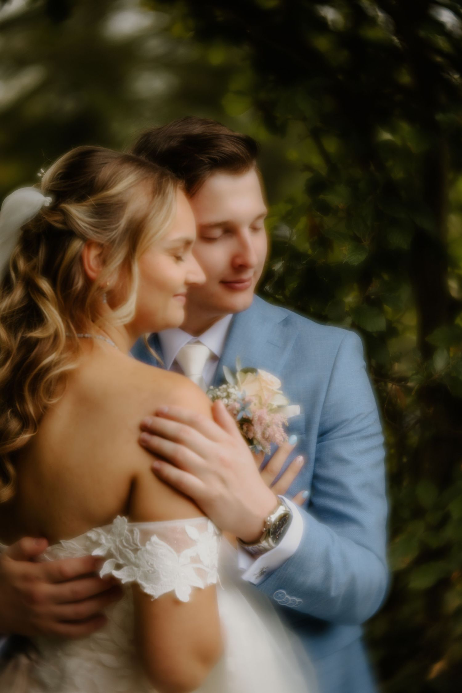 Dromerig portret van een bruidspaar dat elkaar omhelst tussen het groen