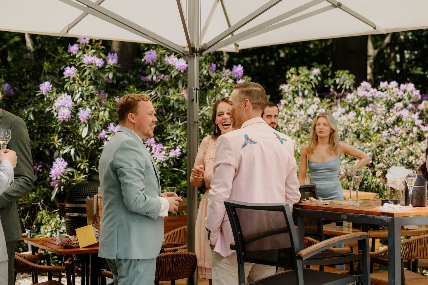 Bruiloftsgasten staan samen gezellig te kletsen op een buitenborrel.