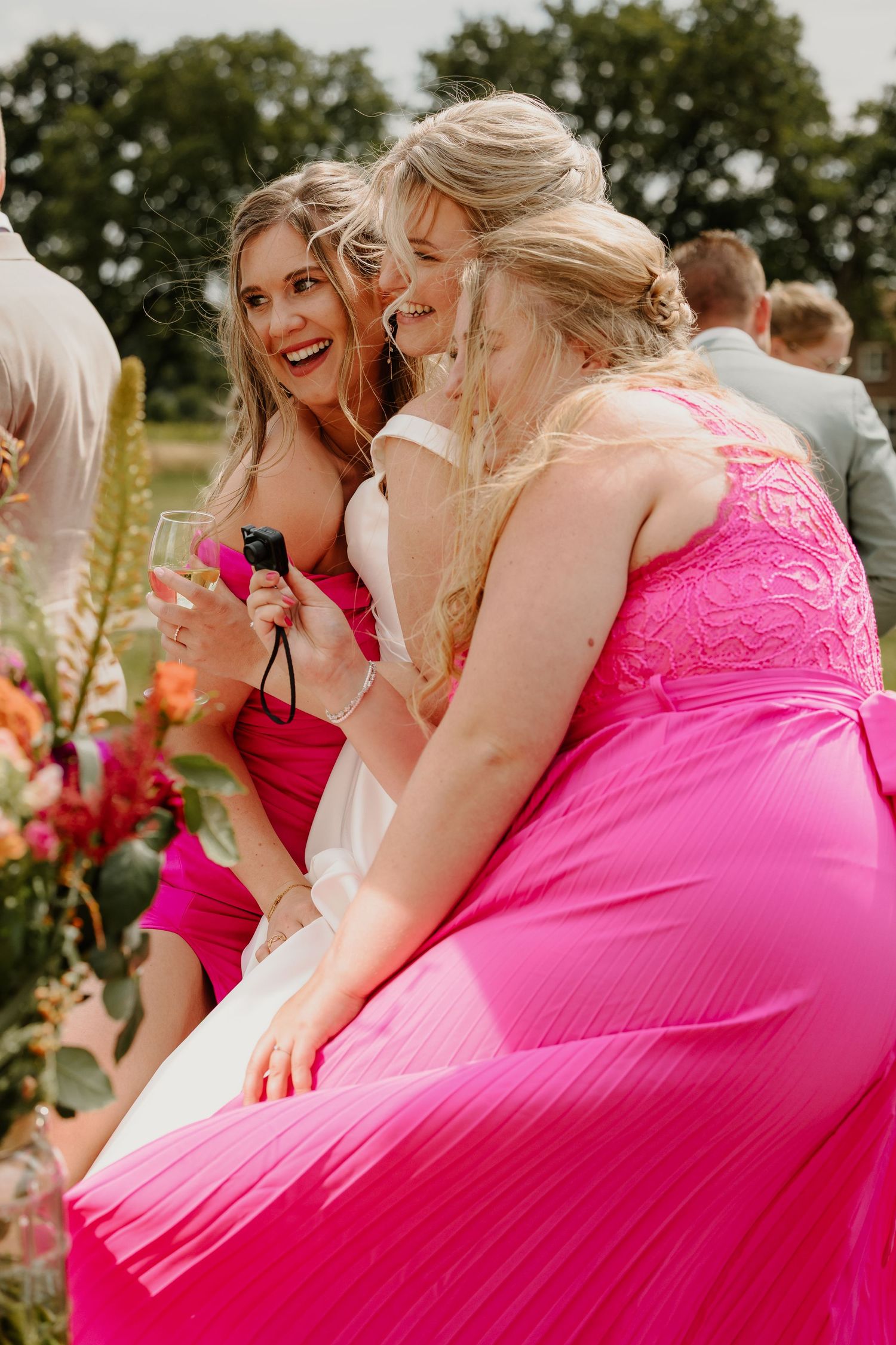 De bruid en haar bruidsmeisjes in roze jurken poseren voor een selfie.