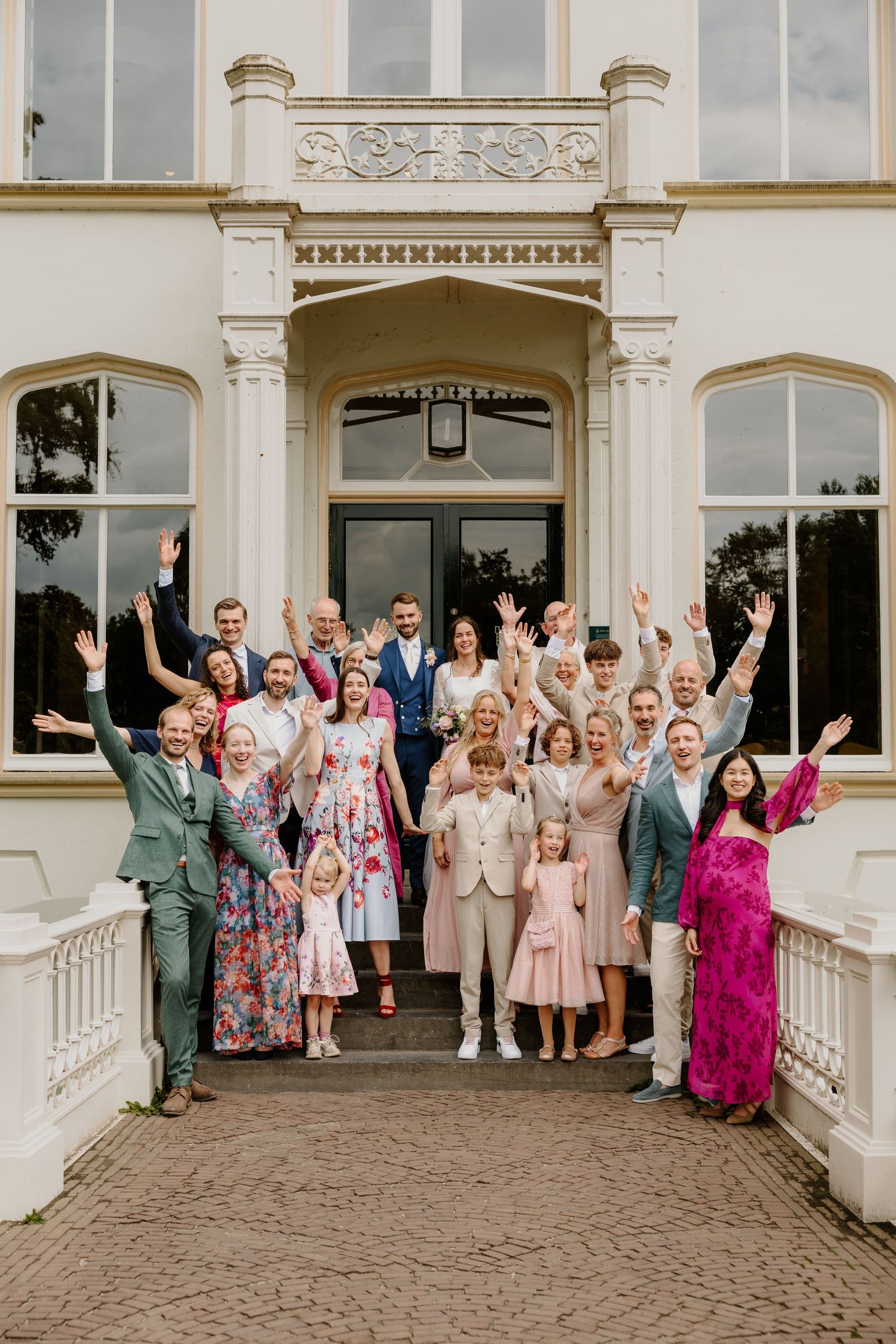 Bruidspaar poseert samen met hun gasten voor de trouwlocatie Huis Scherpenzeel