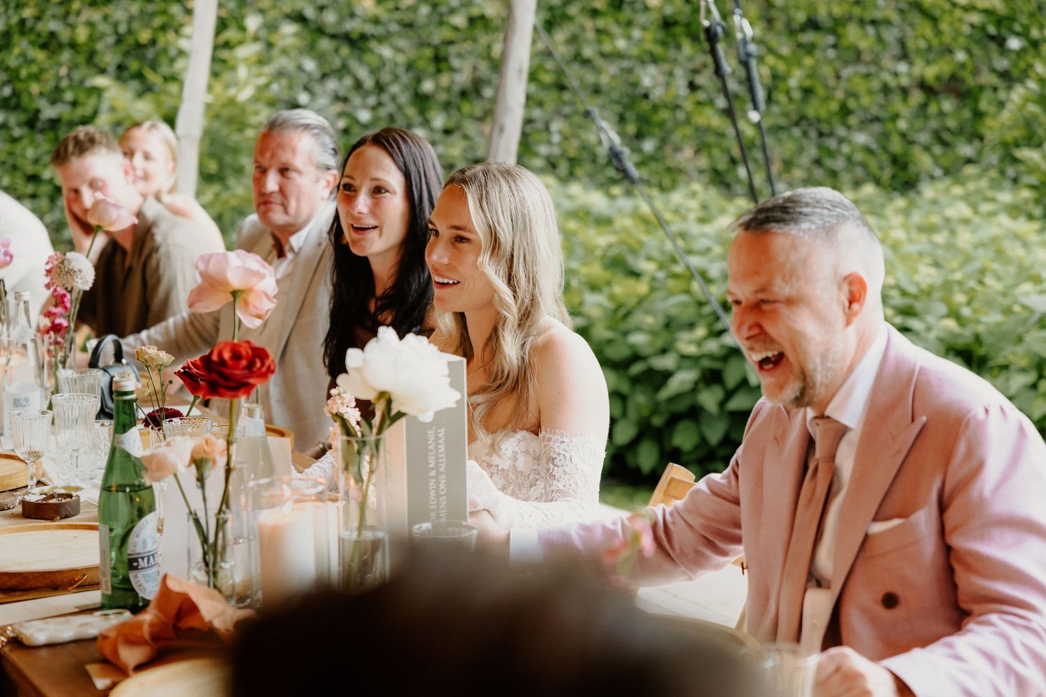 Bruidegom en gasten luisteren naar een speech tijdens het bruiloftsdiner