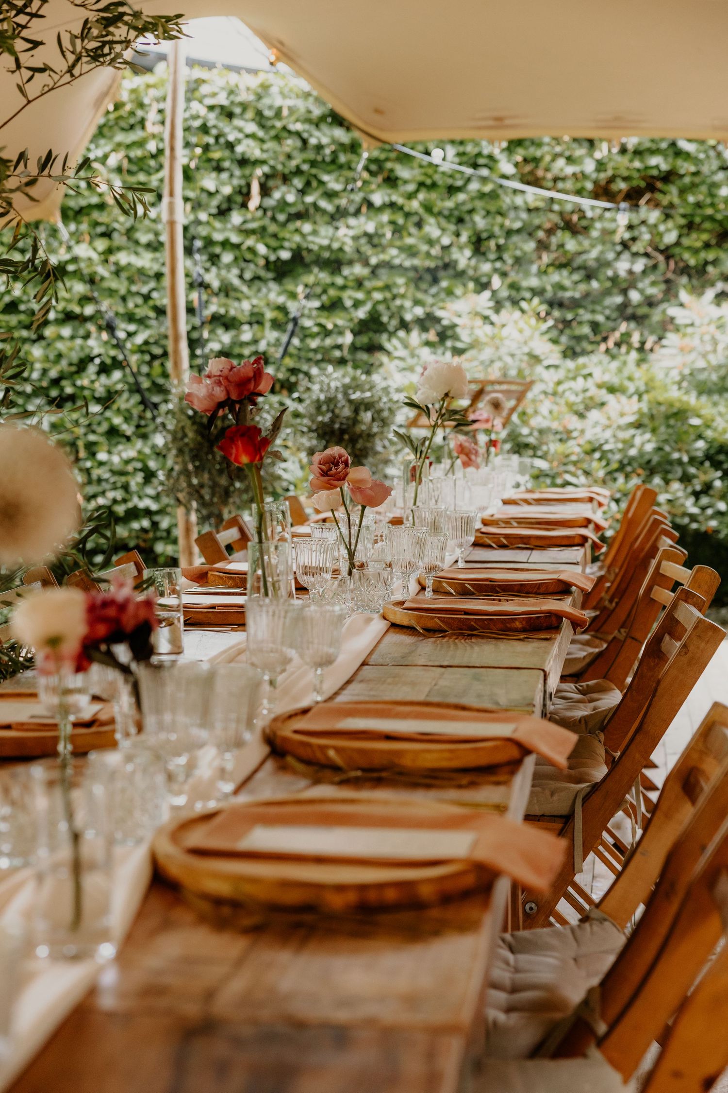 Houten stoelen en gedekte tafels voor een diner op een buitenbruiloft