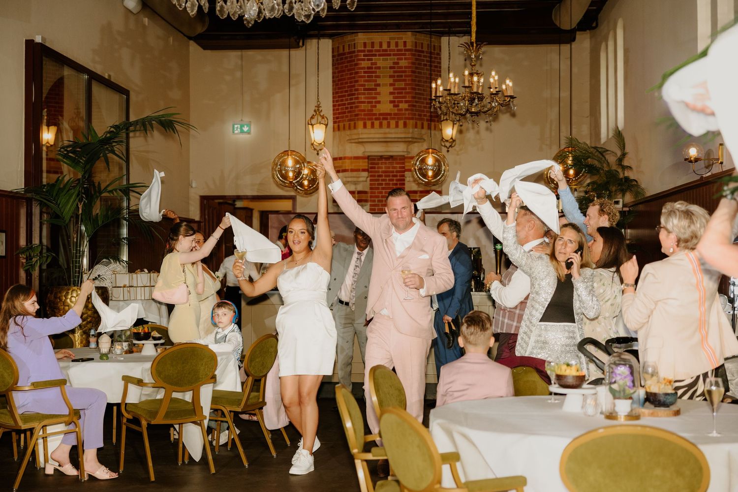 Bruidspaar en bruiloftsgasten zwaaien met servetten tijdens het feest