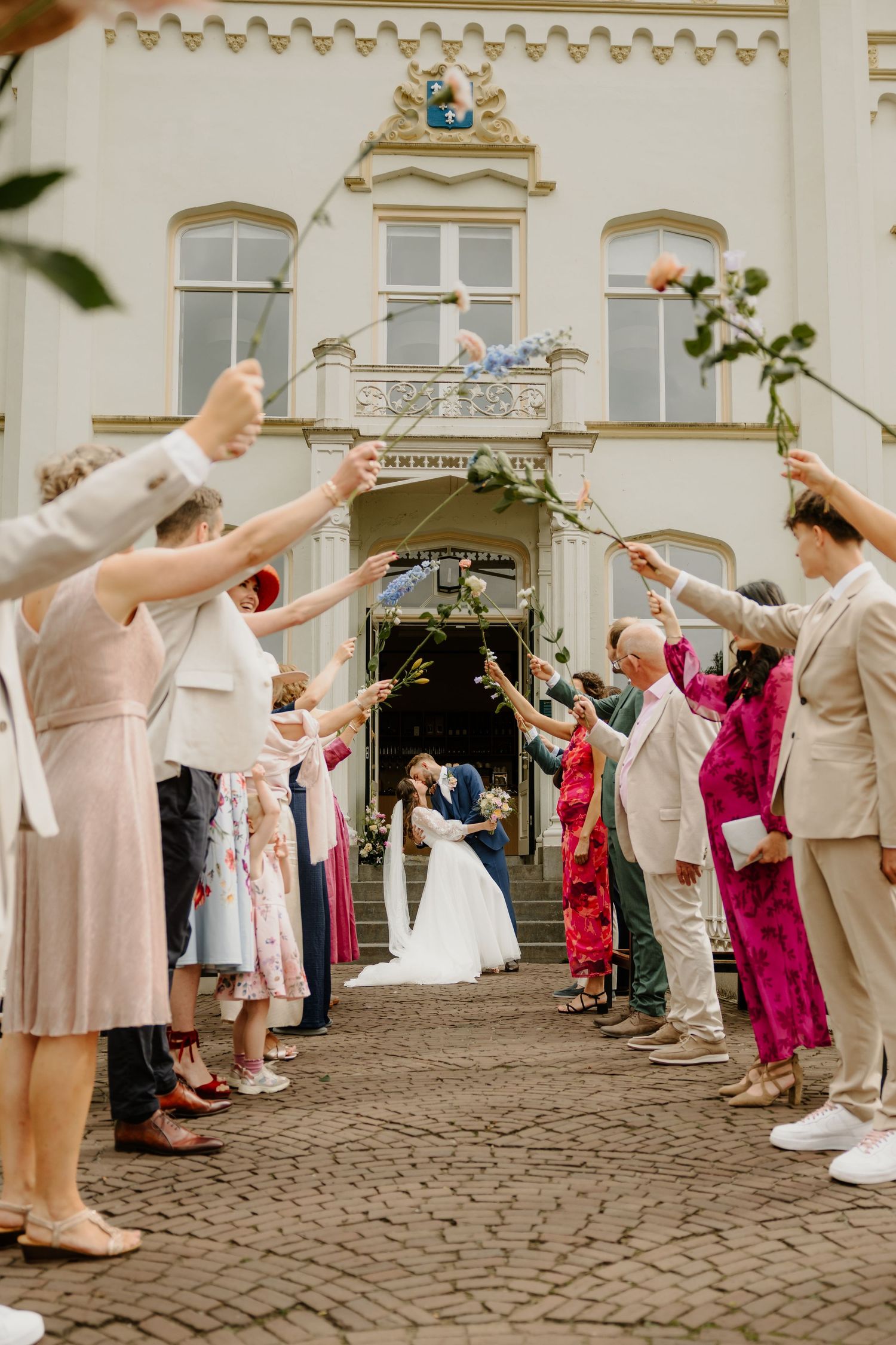 Bruidspaar kust elkaar tussen juichende gasten door na de ceremonie