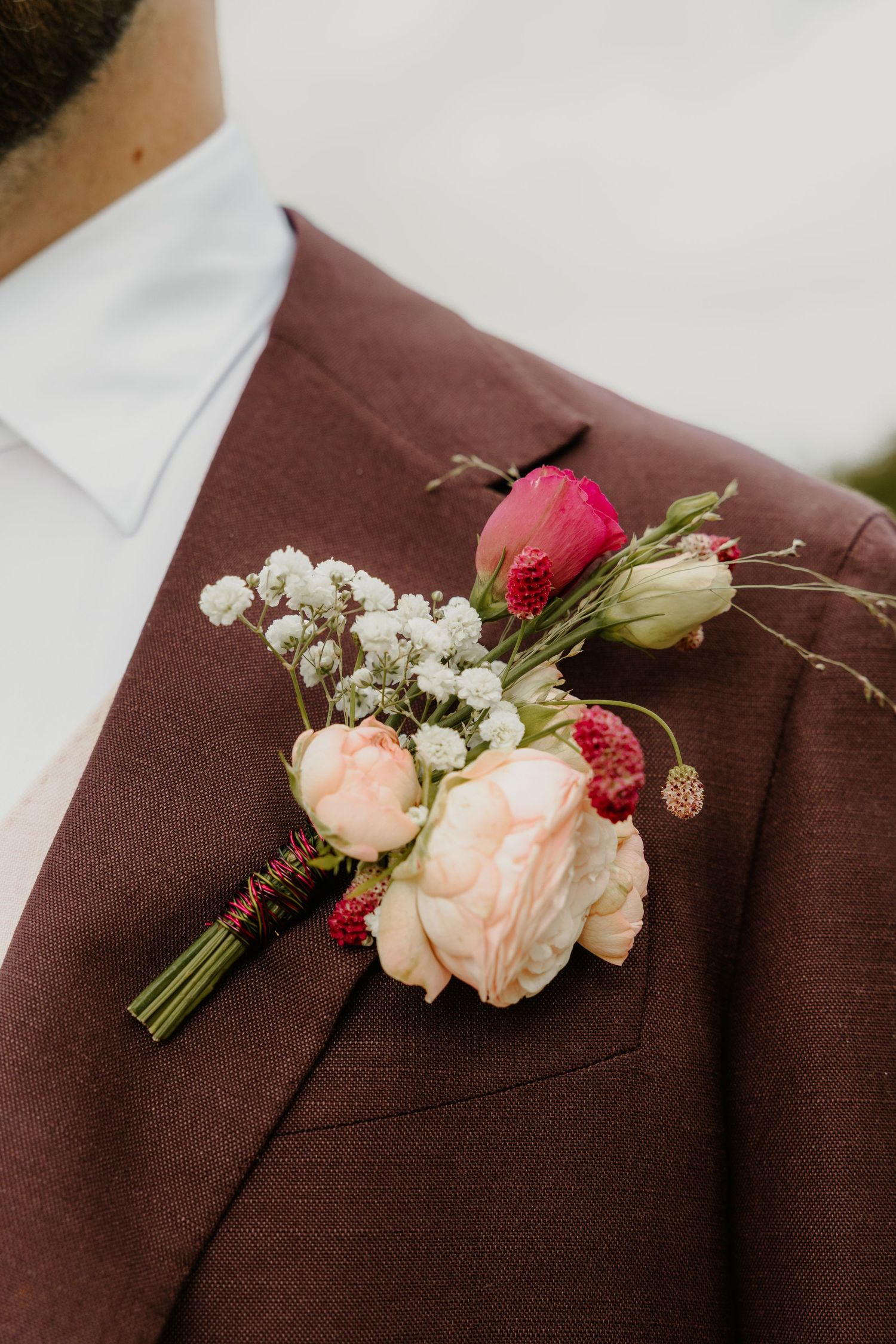 Detail van een boutonnière met bloemen op het pak van de bruidegom