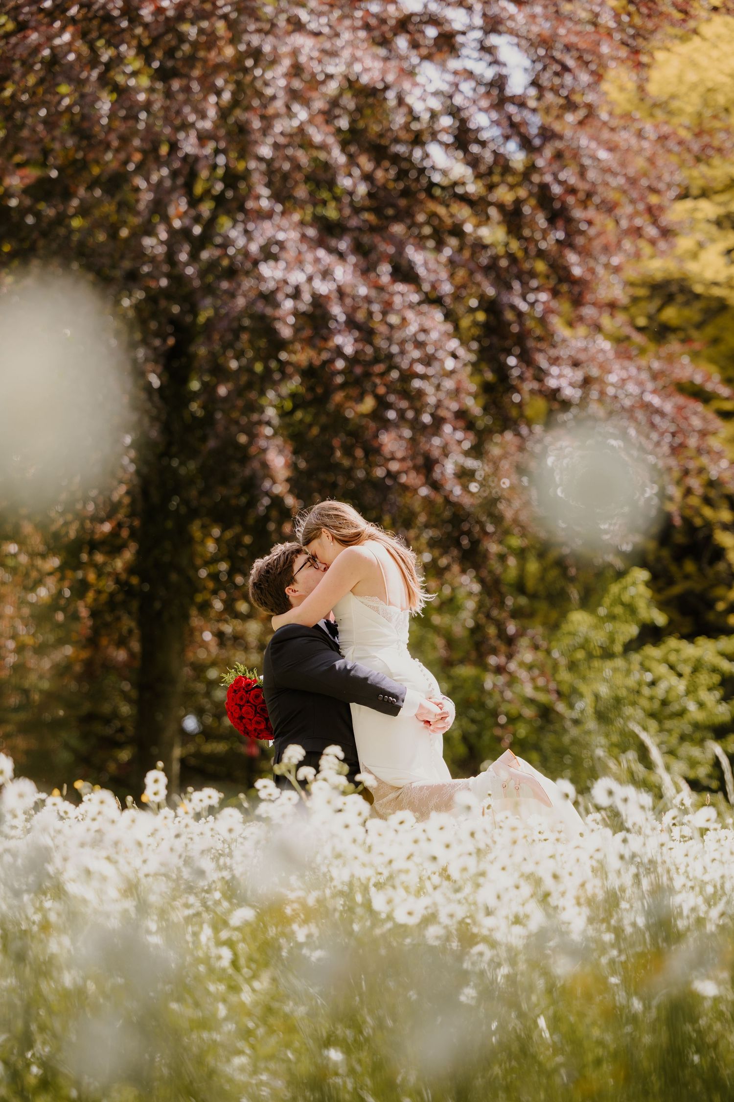 Bruidspaar tussen een zee van bloeiende bloemen tijdens hun trouwfotoshoot