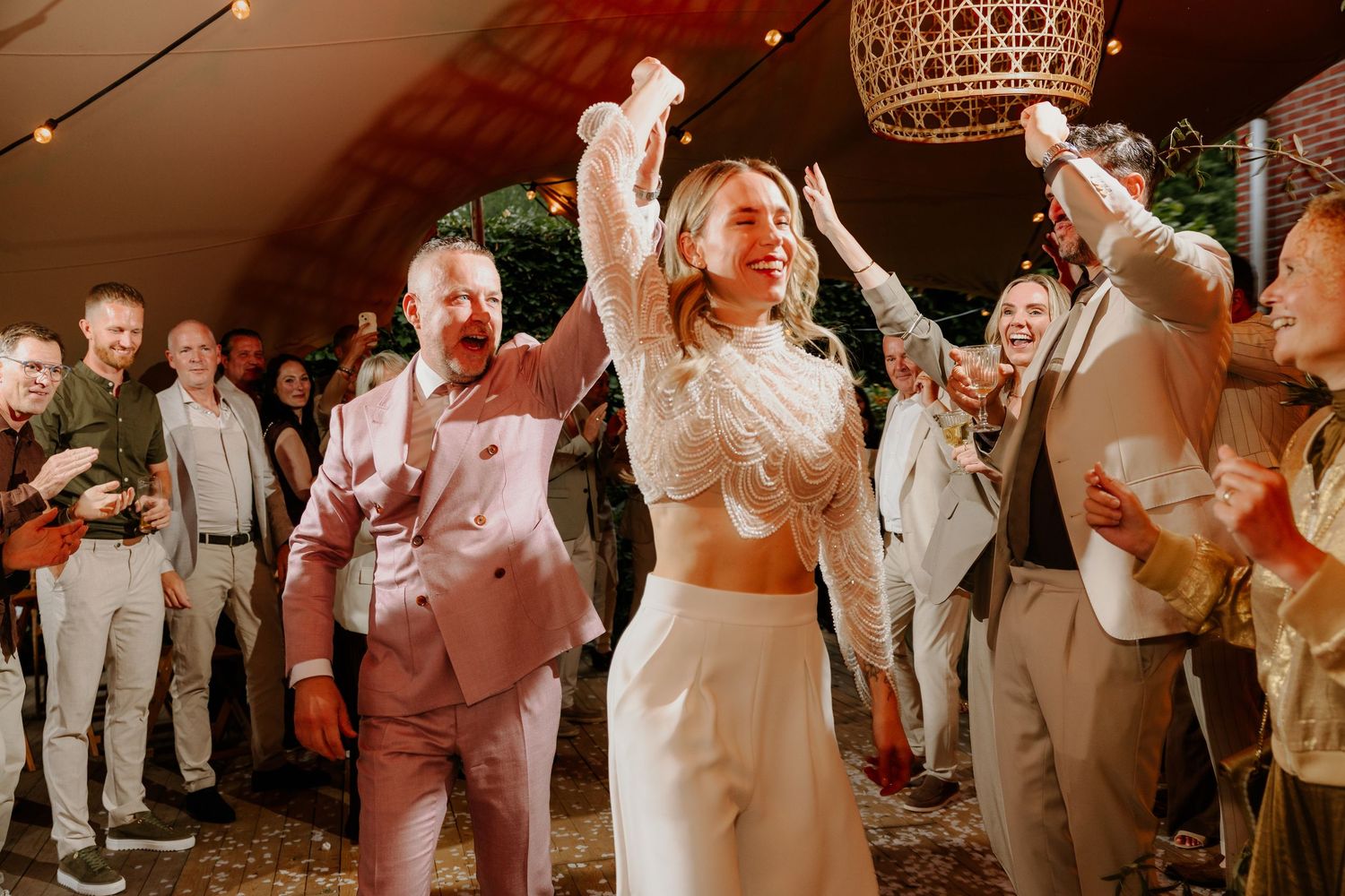 Bruid en bruidegom dansen samen tussen hun feestende bruiloftsgasten