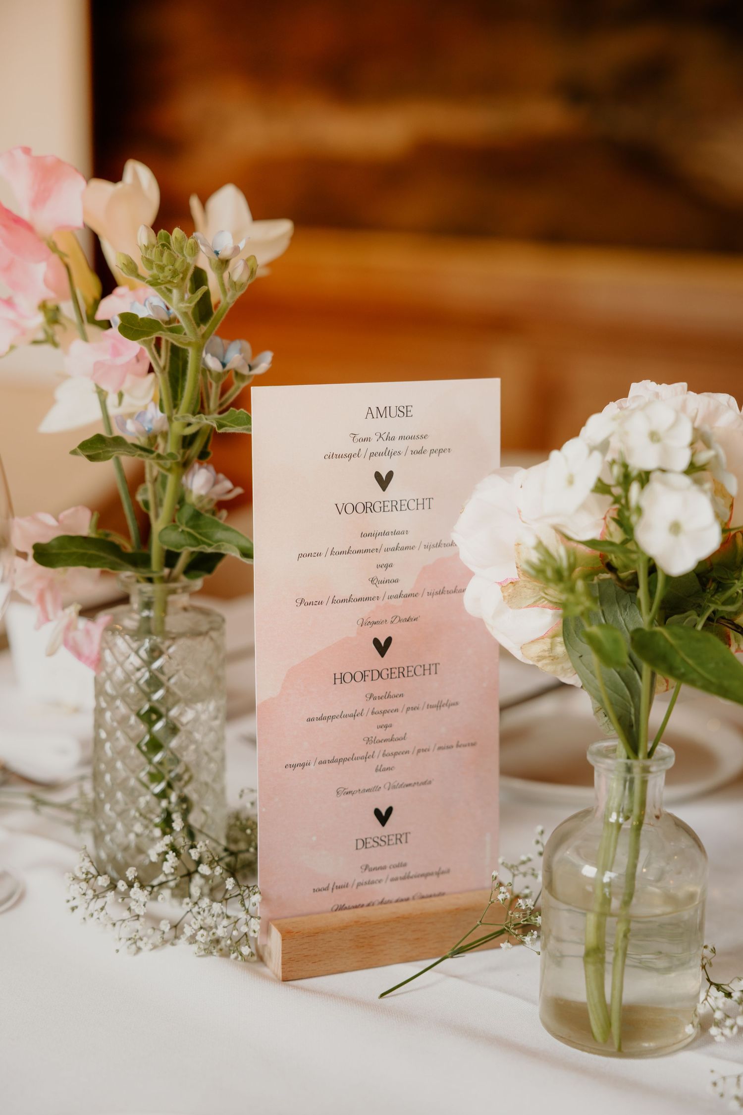 Menukaart tussen bloemen en tafeldecoratie tijdens het bruiloftsdiner