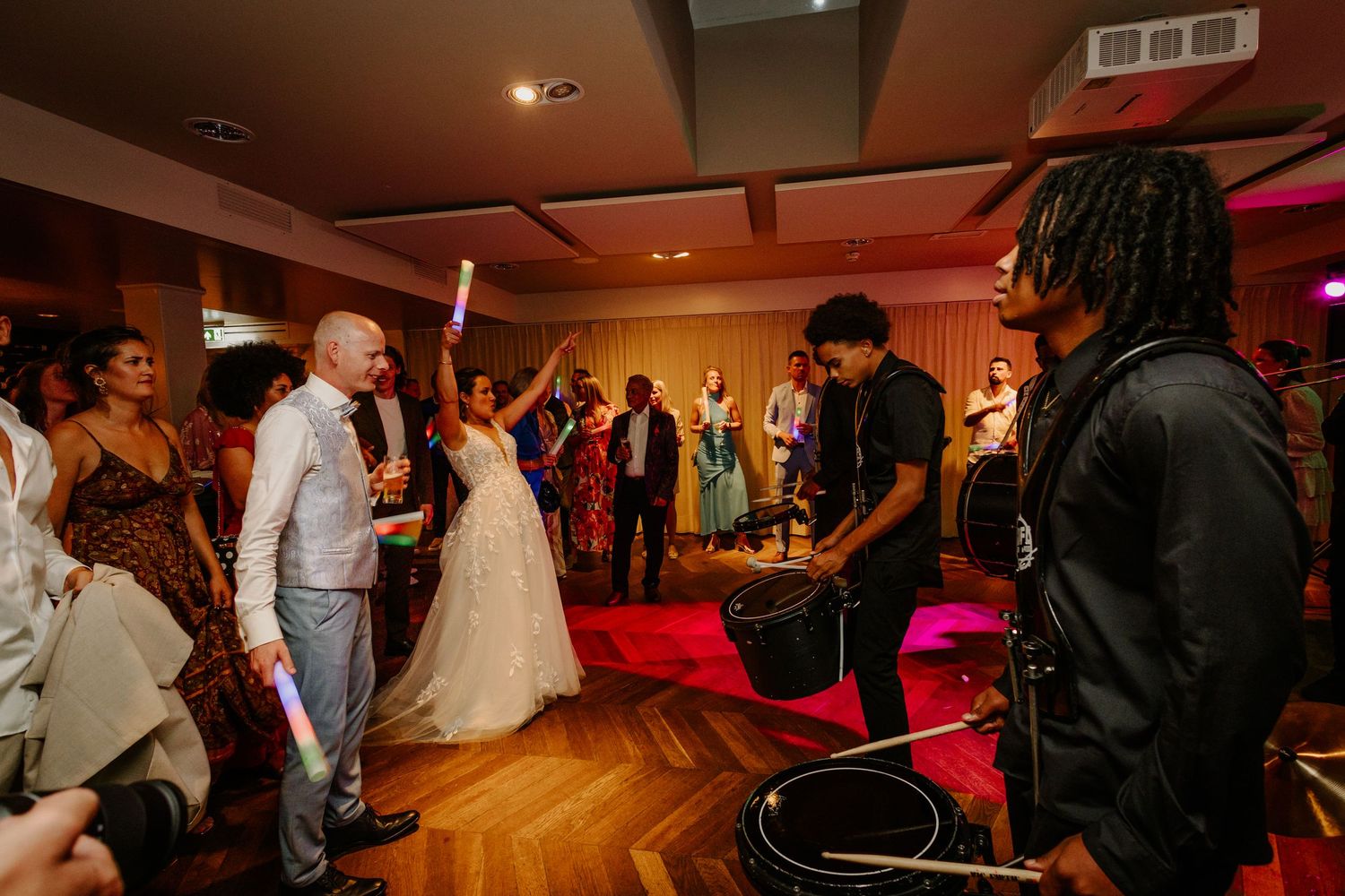Bruid danst en viert feest met gasten in een warm verlichte trouwlocatie.