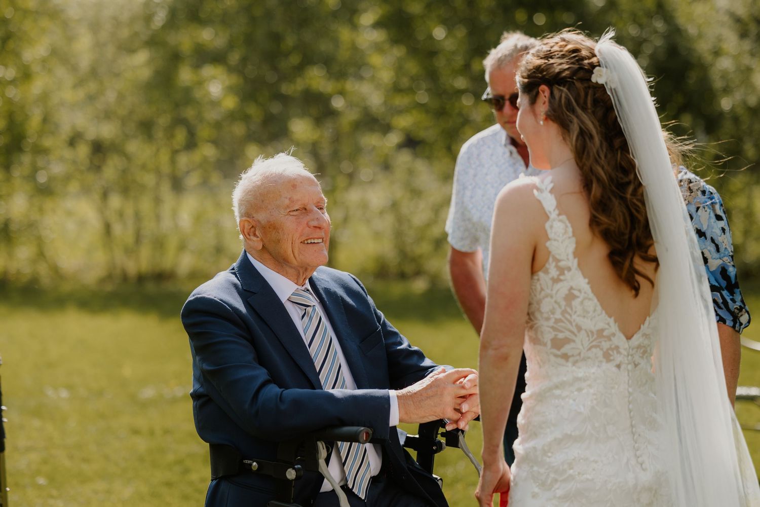 Bruid en haar opa lachen samen tijdens een ontspannen moment buiten