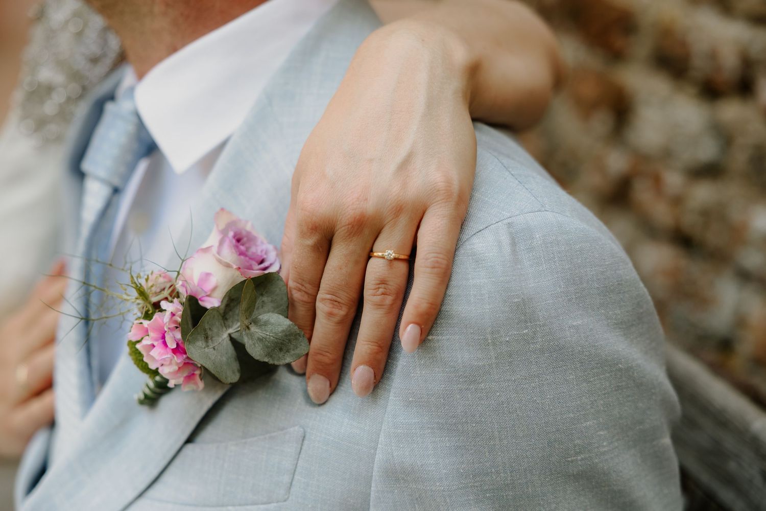 Een trouwring aan een hand naast een corsage