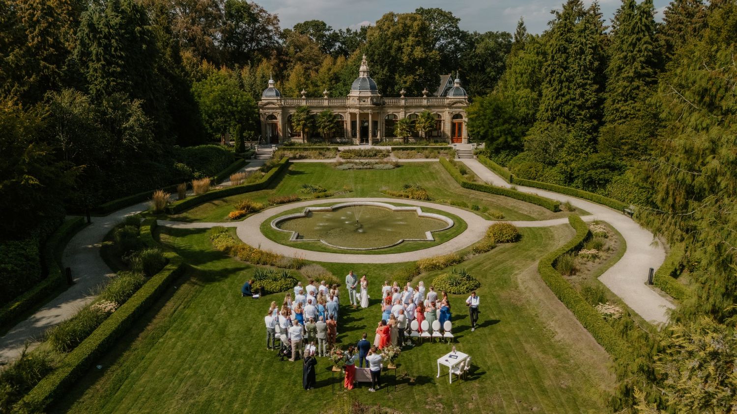 Dronebeeld van een buitenbruiloft in een symmetrische klassieke tuin bij Oranjerie Hydepark