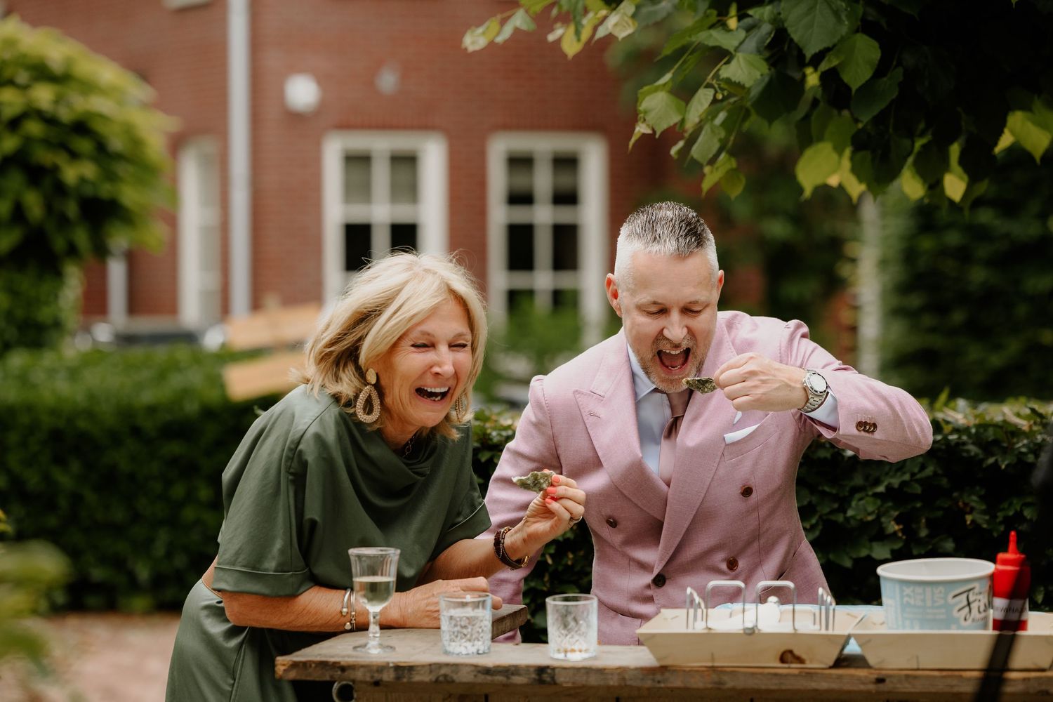 Een gast en de bruidegom moeten lachen terwijl ze oesters eten op zijn bruiloft.