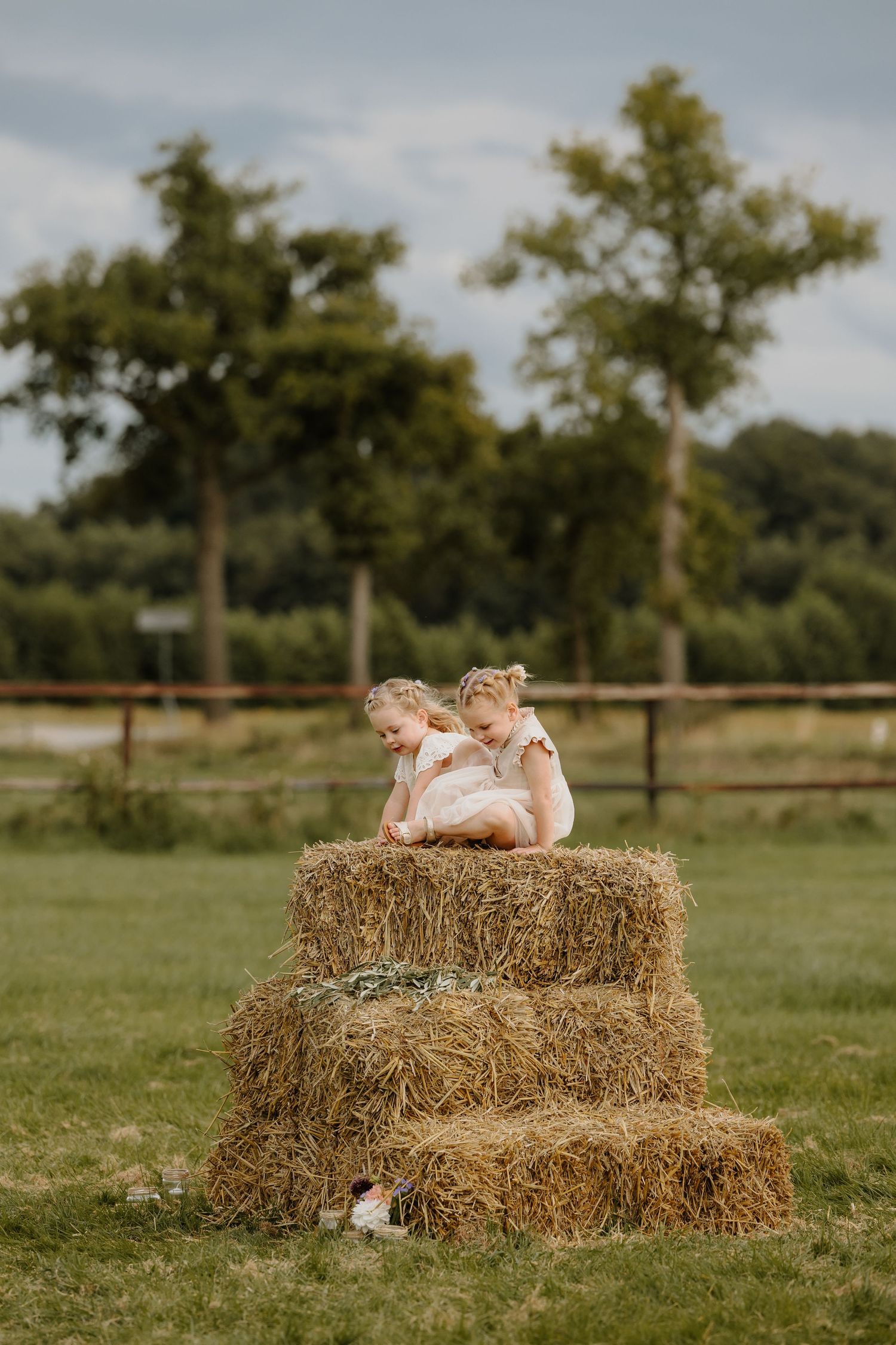 Twee bruidsmeisjes zitten op een stapel hooibalen