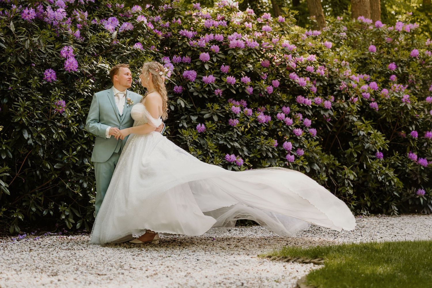 Bruidspaar poseert voor een prachtige bloeiende muur van hortensia's