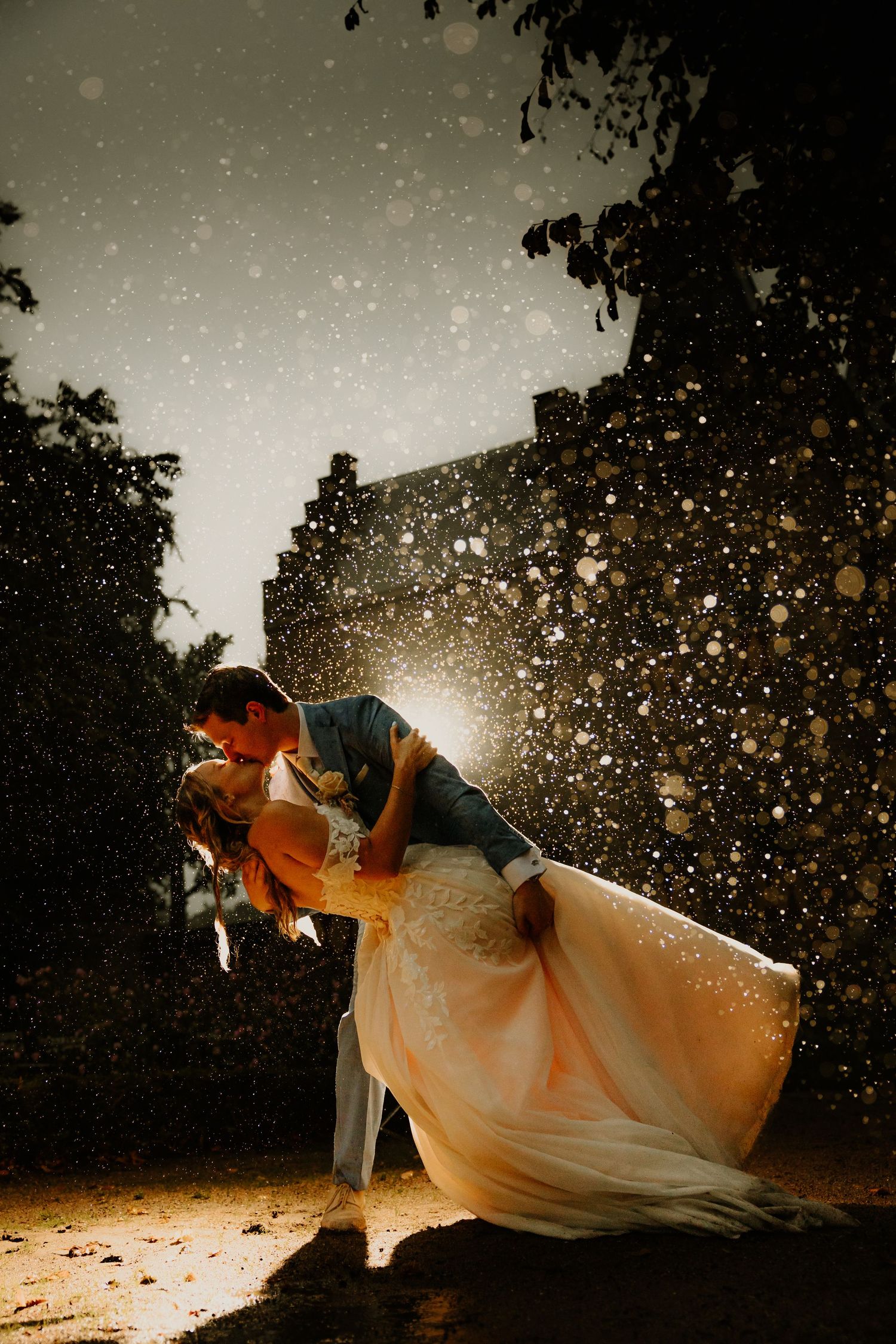 Bruidspaar kust elkaar tijdens een creatieve trouwfoto in de regen