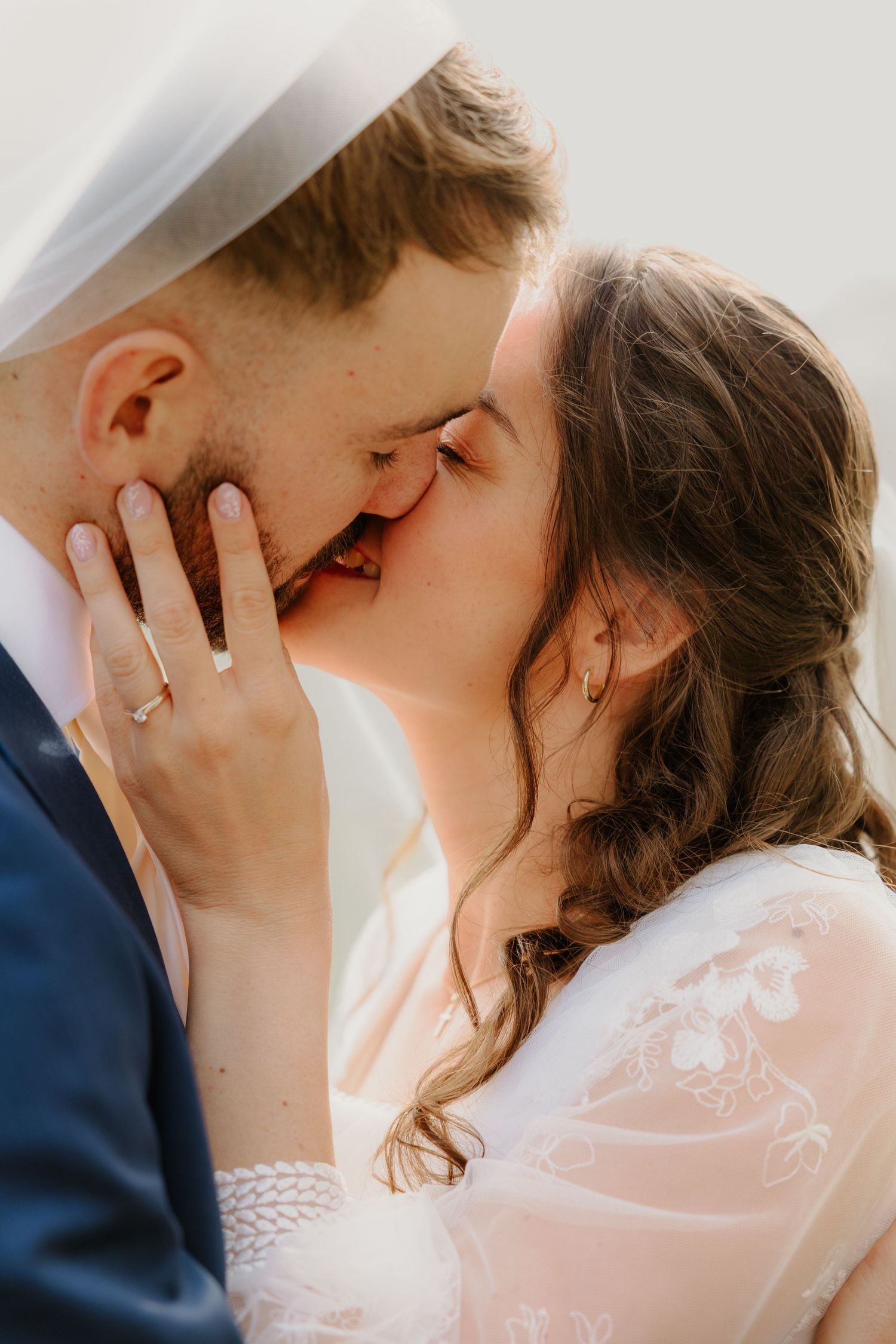 De bruid kust de bruidegom vol liefde onder haar sluier