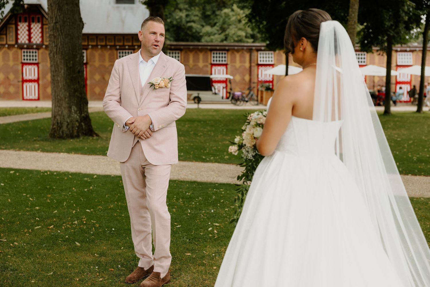 Bruid loopt naar haar partner tijdens een first look in de tuin