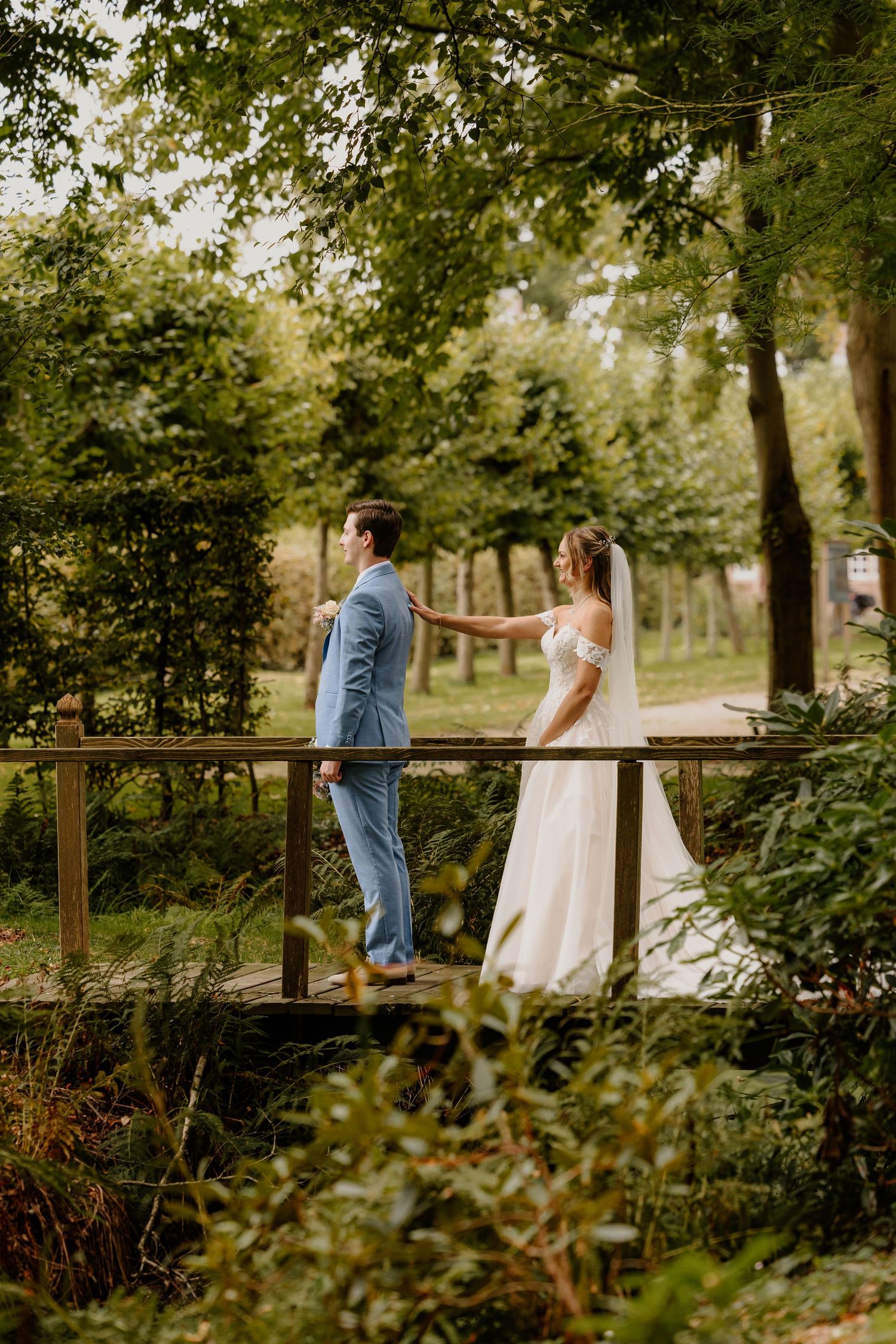 Bruid loopt naar haar bruidegom toe voor hun first look op een houten brug