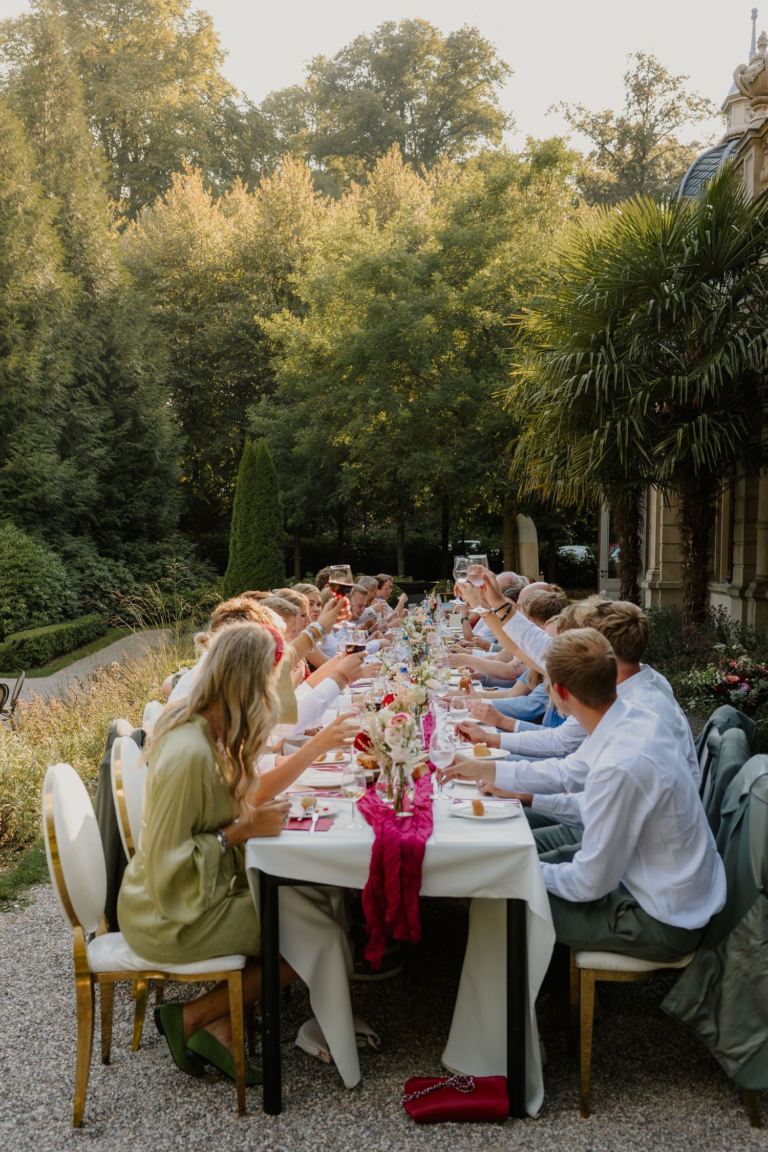 Bruiloftsgasten samen aan tafel in een groene tuin