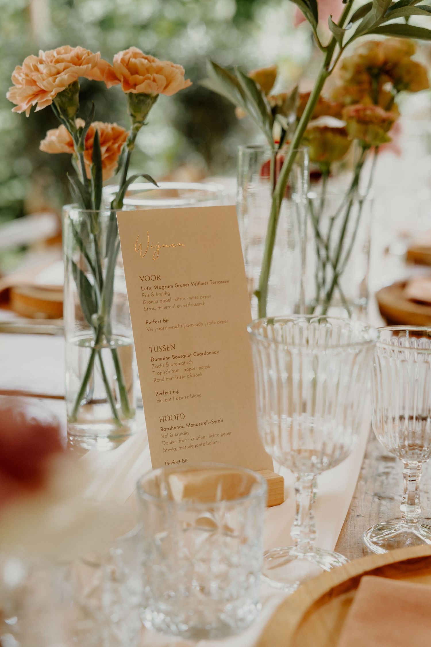 Gedekte dinertafel met bloemen, glaswerk en menukaart tijdens een bruiloft