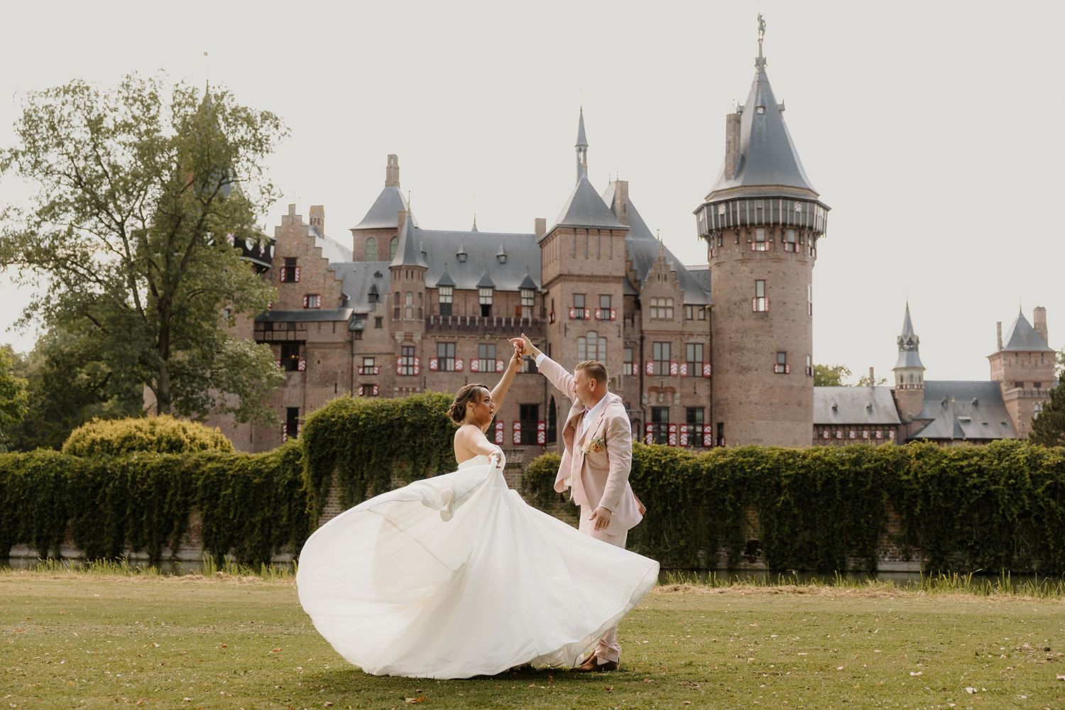 Een bruidspaar danst in prachtige trouwkleding voor Kasteel de Haar in Utrecht