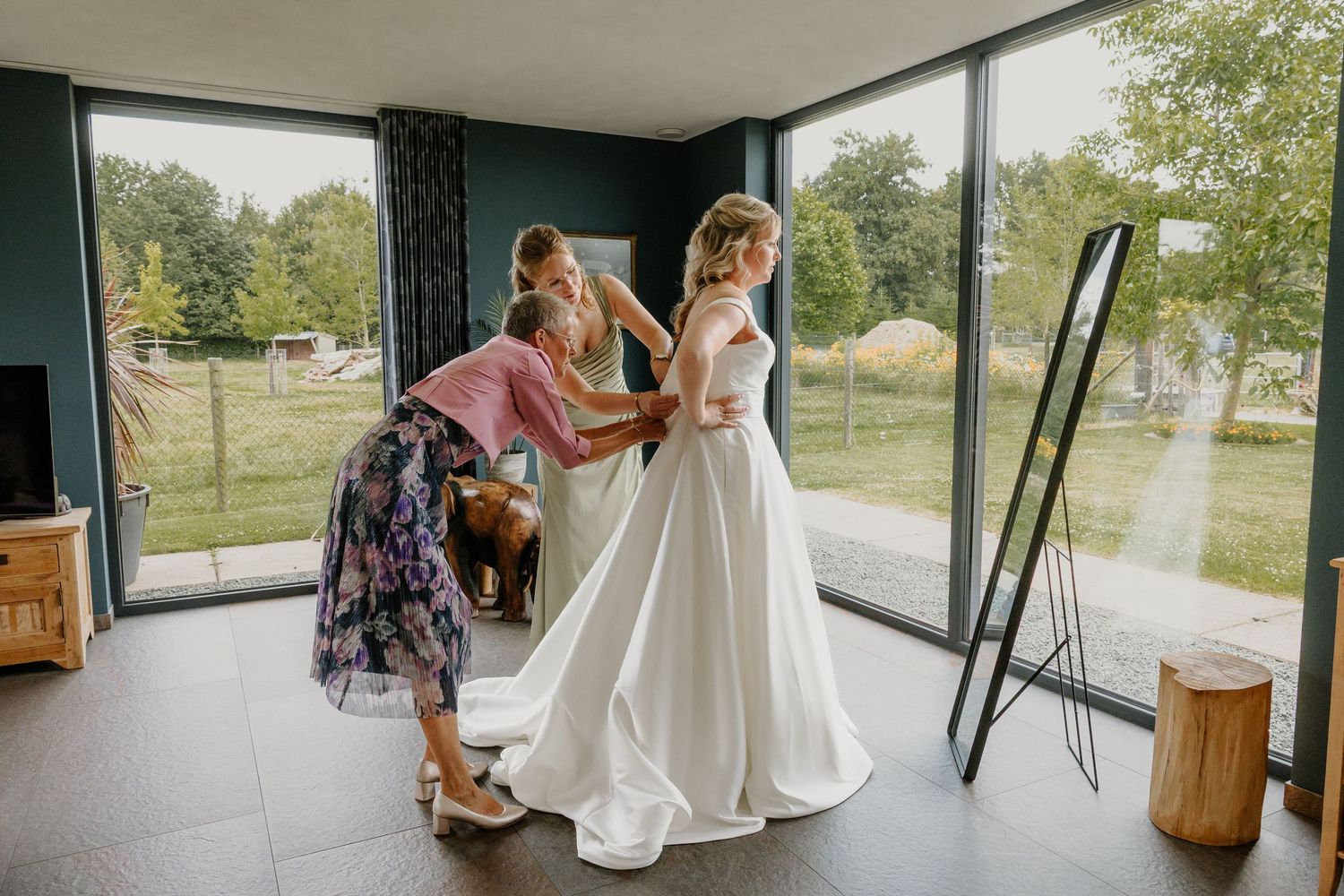 Bruid wordt geholpen met aankleden tijdens de getting ready