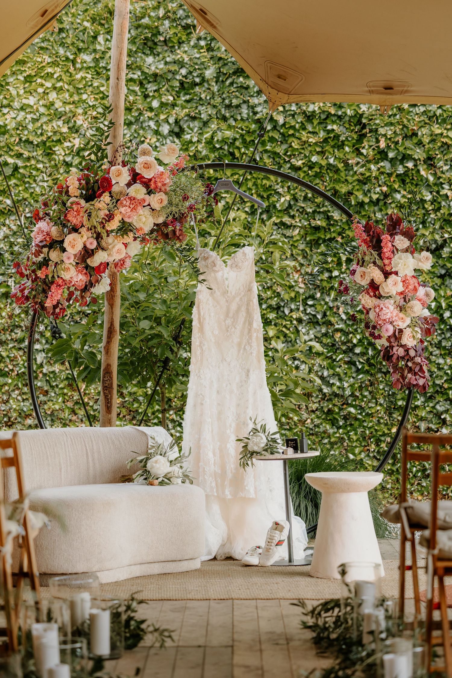Romantische ceremonieopstelling met bloemen voor een buitenbruiloft, de jurk hangt aan de backdrop