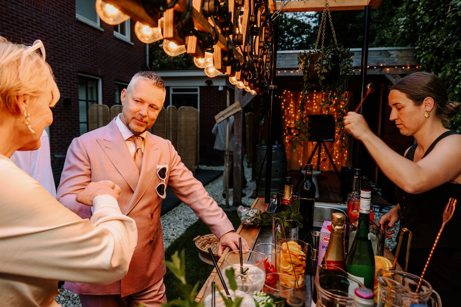 Bruidegom geeft een gast een boks terwijl hij een cocktail haalt aan de bar.