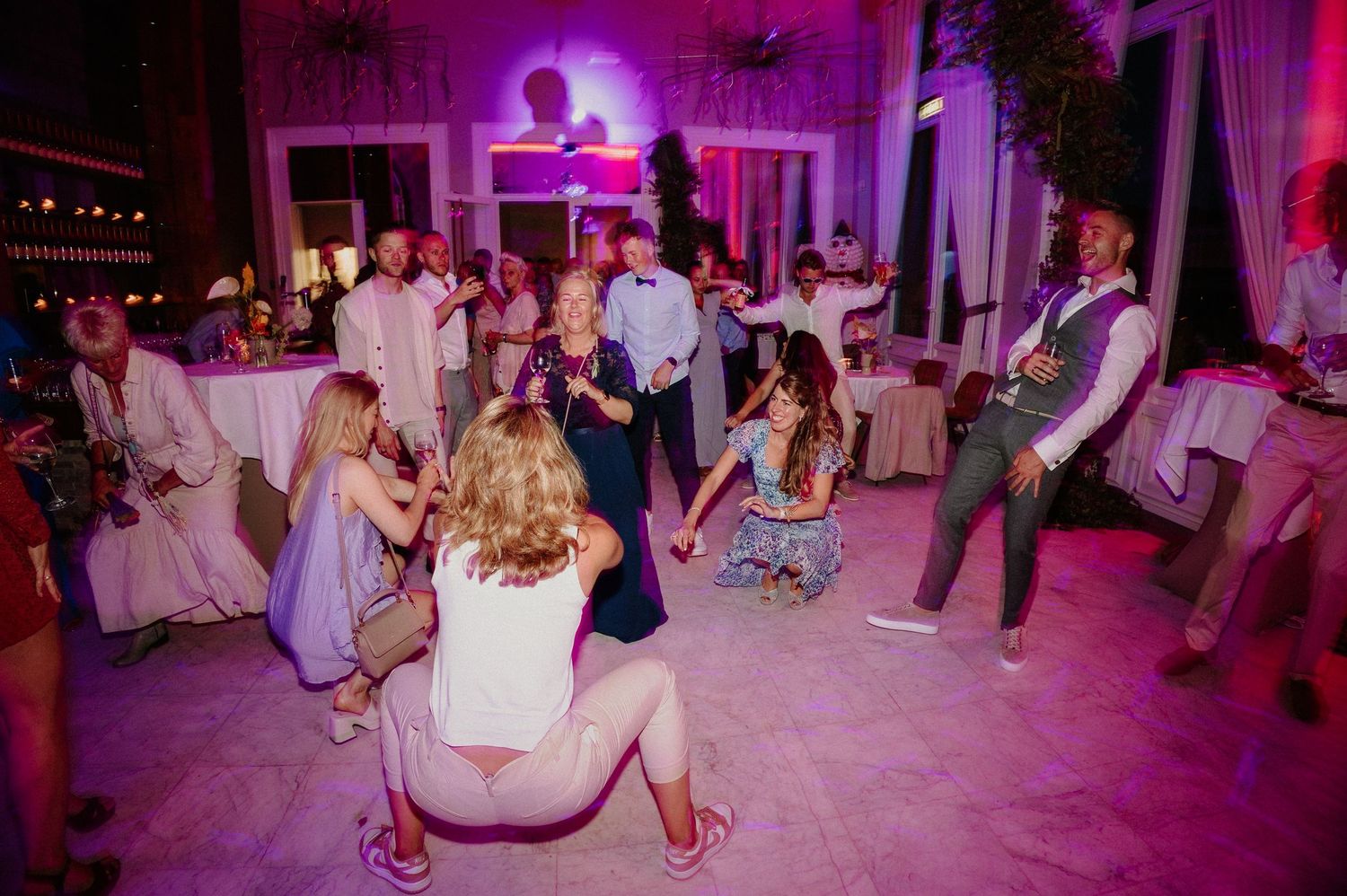 Gasten dansen en lachen samen tijdens een energiek trouwfeest.