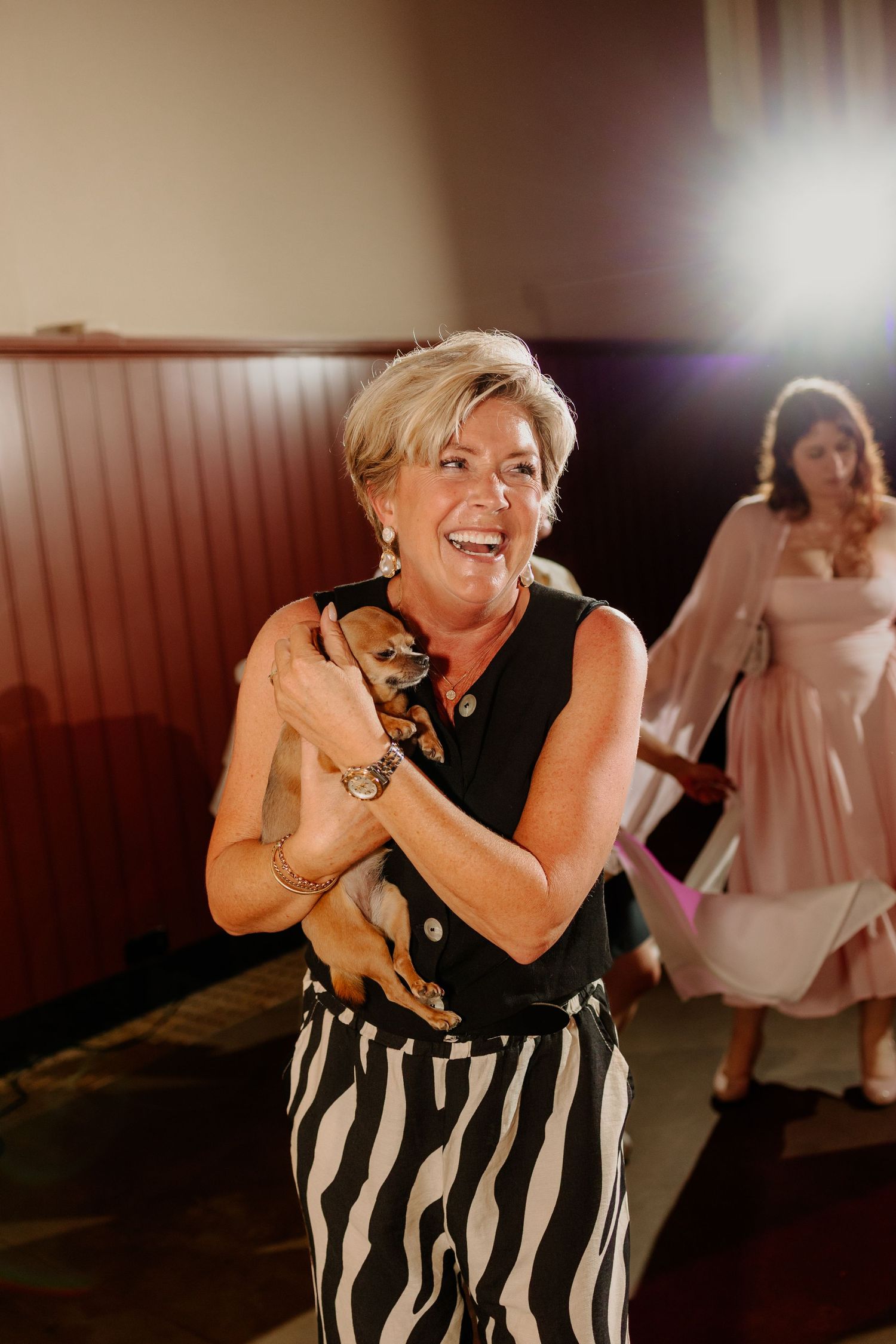 Lachende bruiloftsgast danst enthousiast met haar hondje op de dansvloer