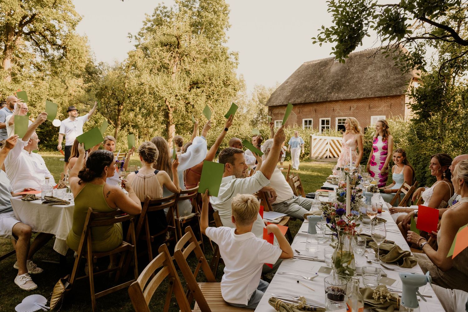 Gasten proosten tijdens een zomers bruiloftsdiner in de tuin