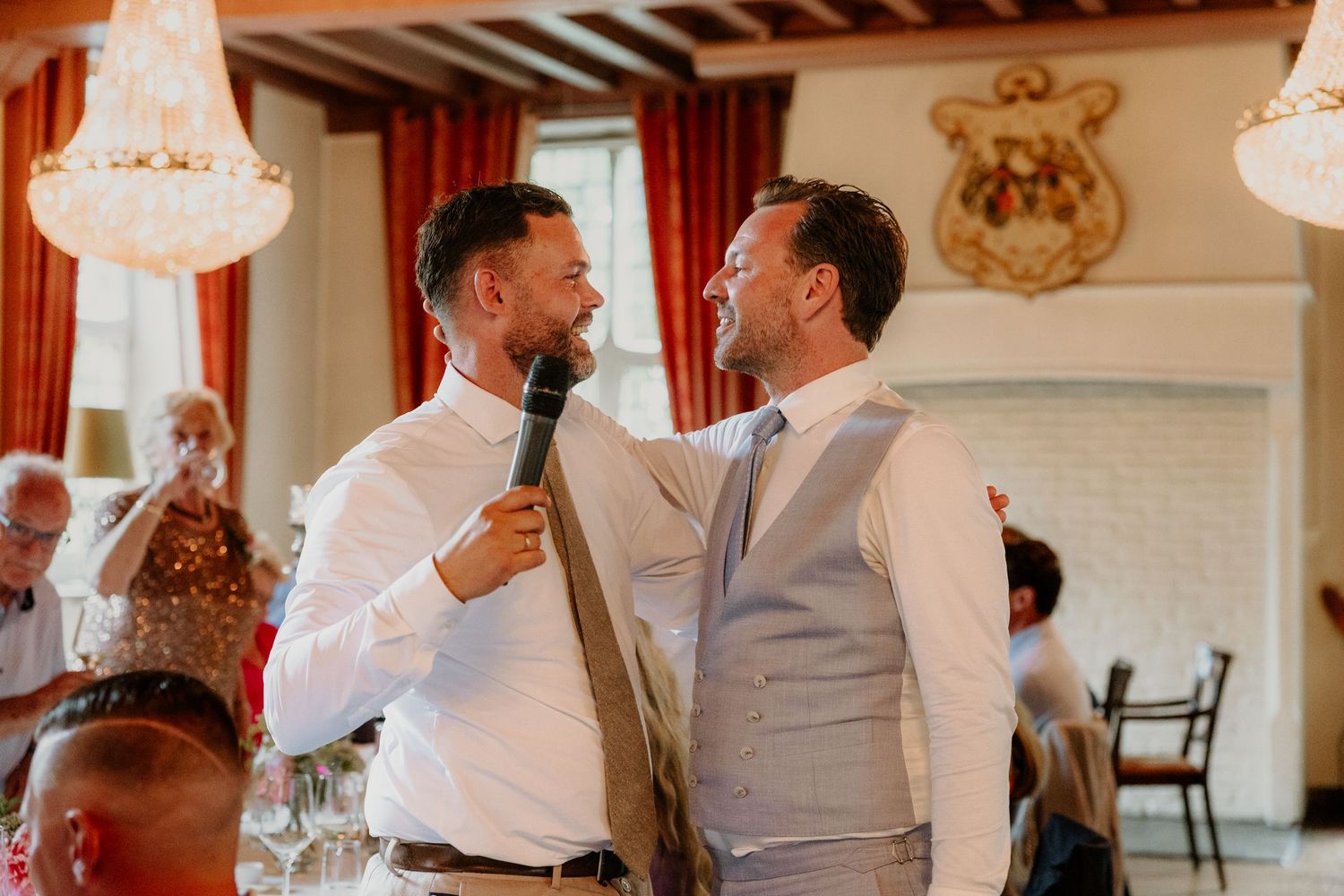 Bruidegom lacht samen met beste vriend tijdens een speech op de bruiloft