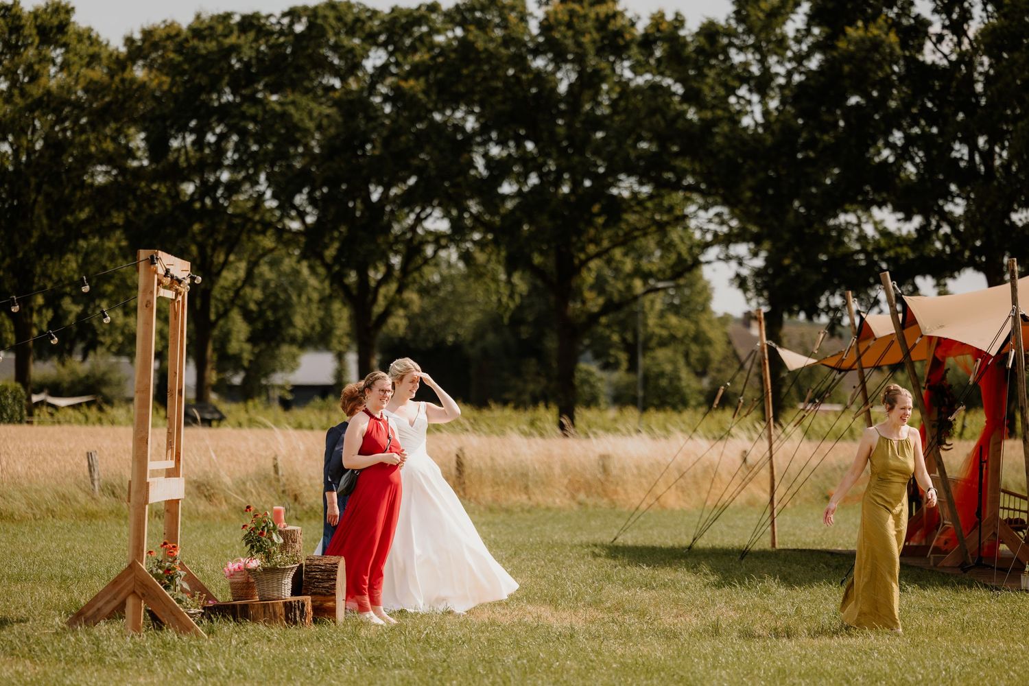 De bruid poseert met haar vriendinnen voor een backdrop terwijl een andere vriendin met haar telefoon een foto maakt.