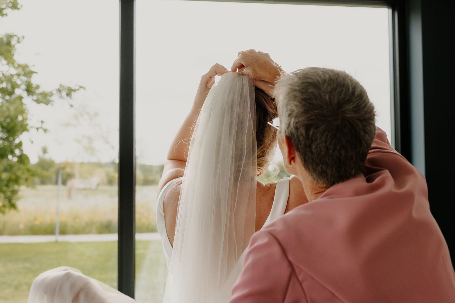 Bruid krijgt hulp met haar sluier tijdens de voorbereidingen voor de bruiloft