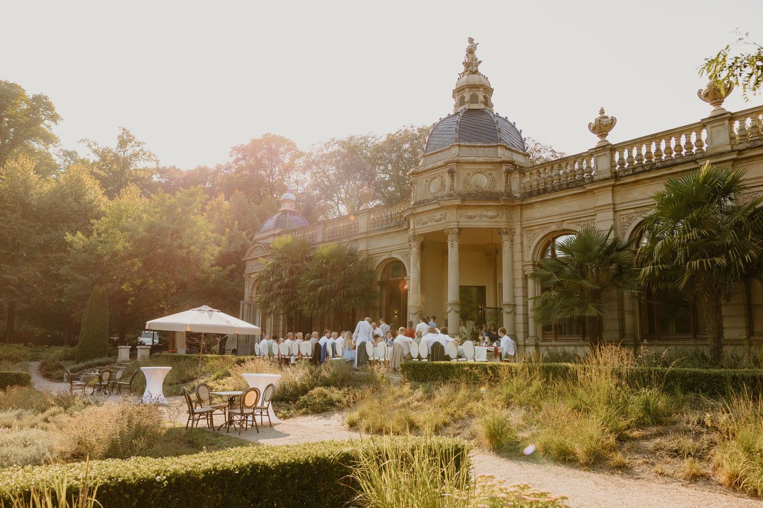 asten dineren buiten bij een klassiek paviljoen van Oranjerie Hydepark tijdens een zomerse bruiloft