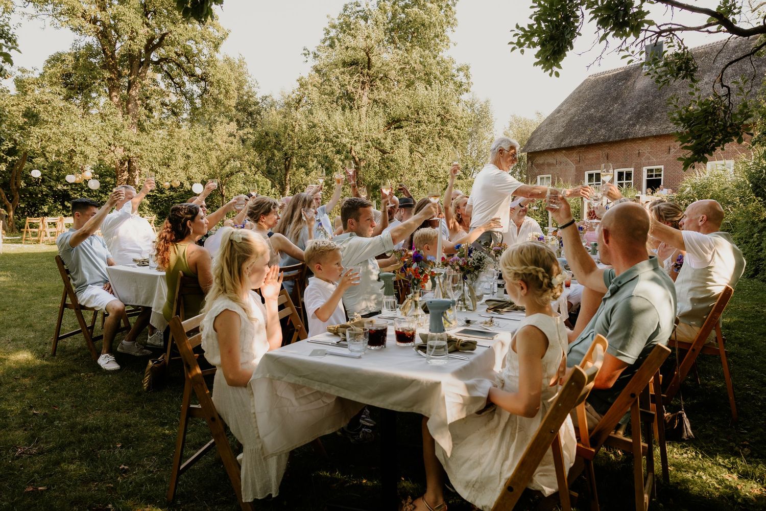 Lange dinertafel met bruiloftsgasten tijdens een buitenbruiloft