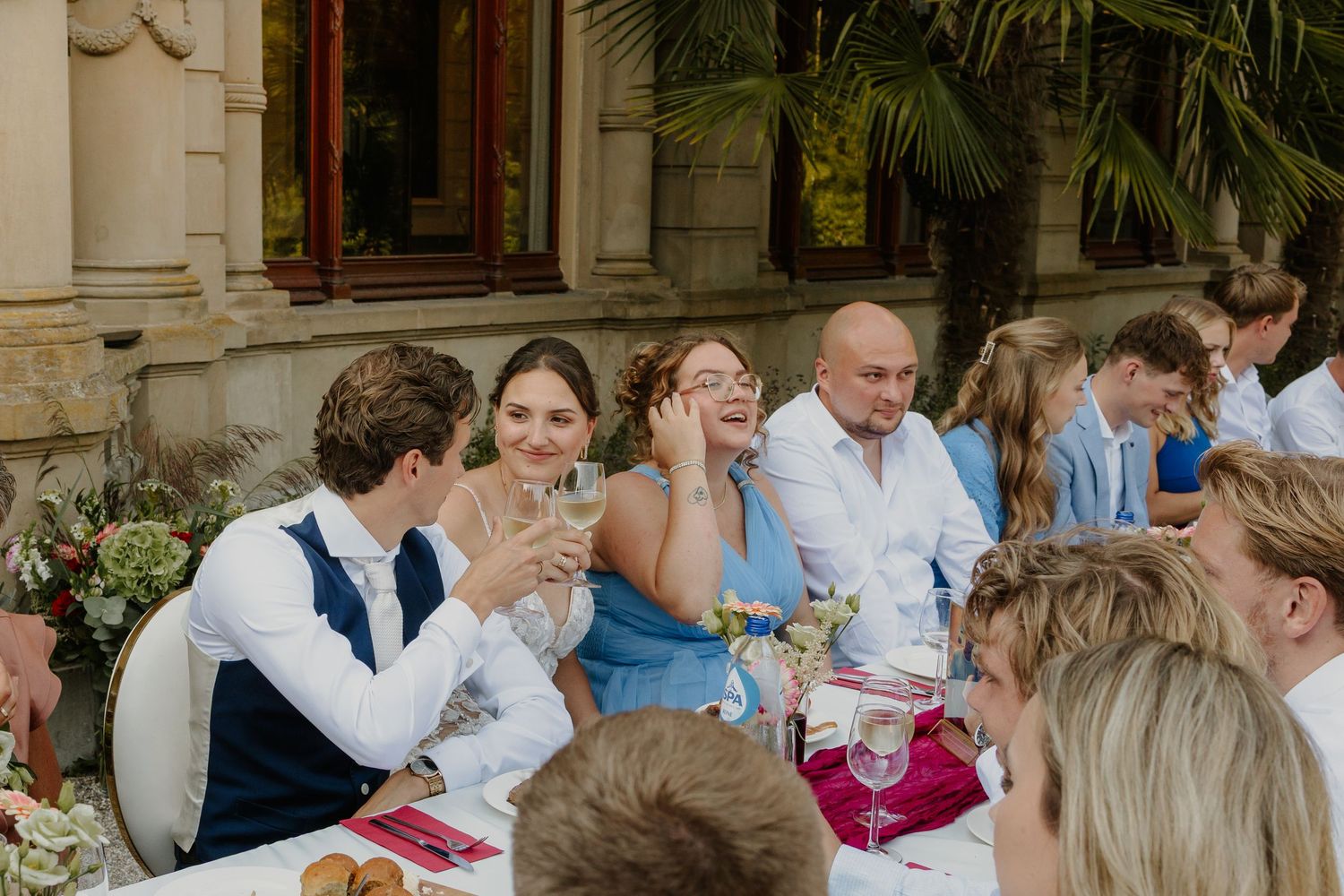 Het bruidspaar proost tijdens het diner op hun zomerse bruitenbruiloft
