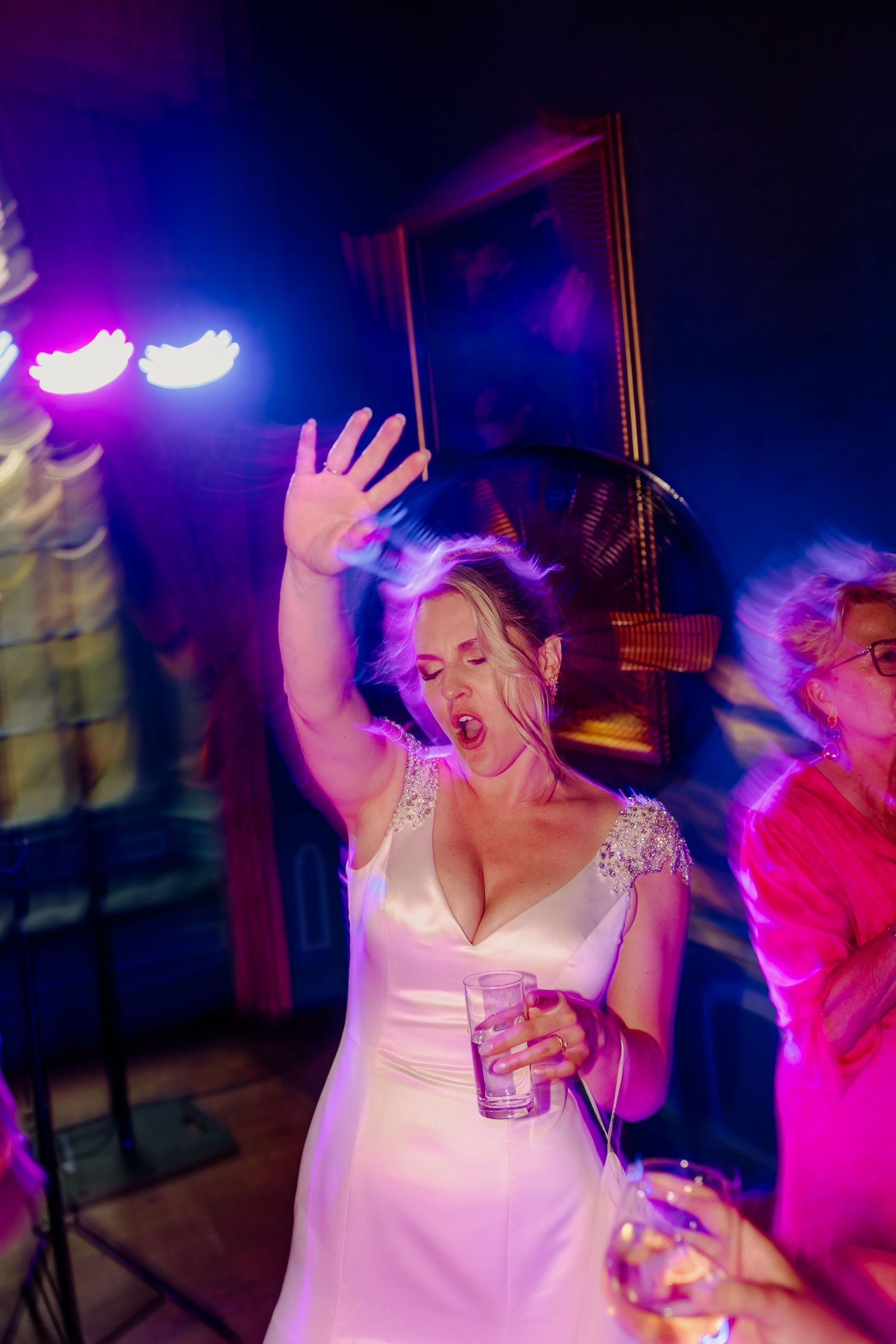 Dansende bruid met drankje in haar hand tijdens het trouwfeest