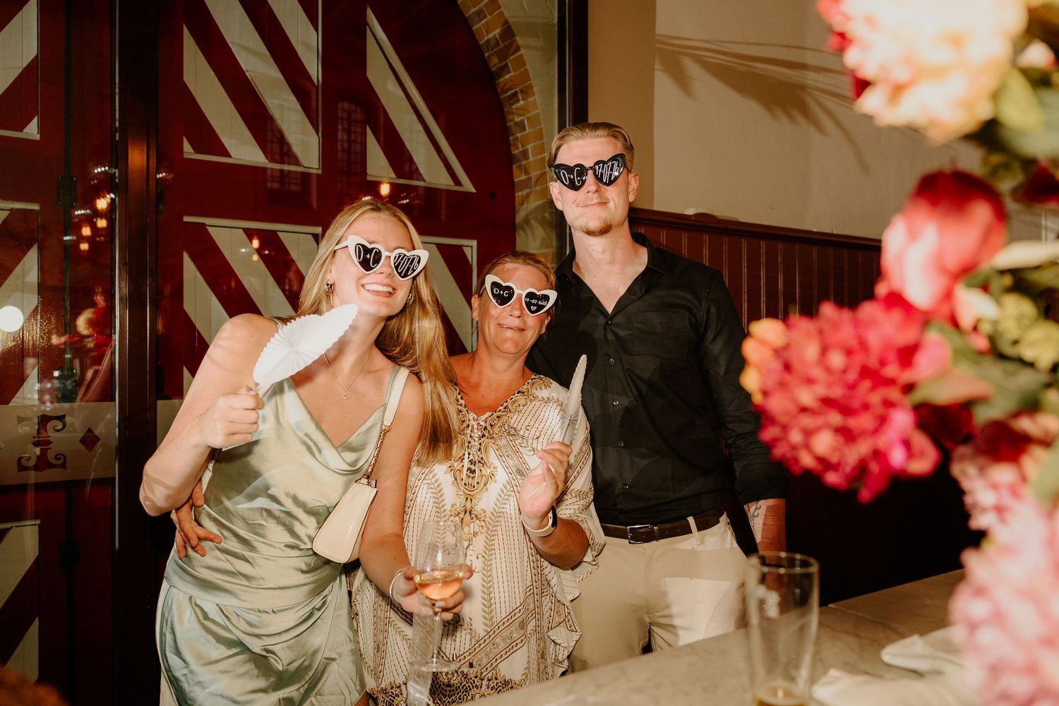 Drie bruiloftsgasten met zonnebrillen tijdens het diner en feest