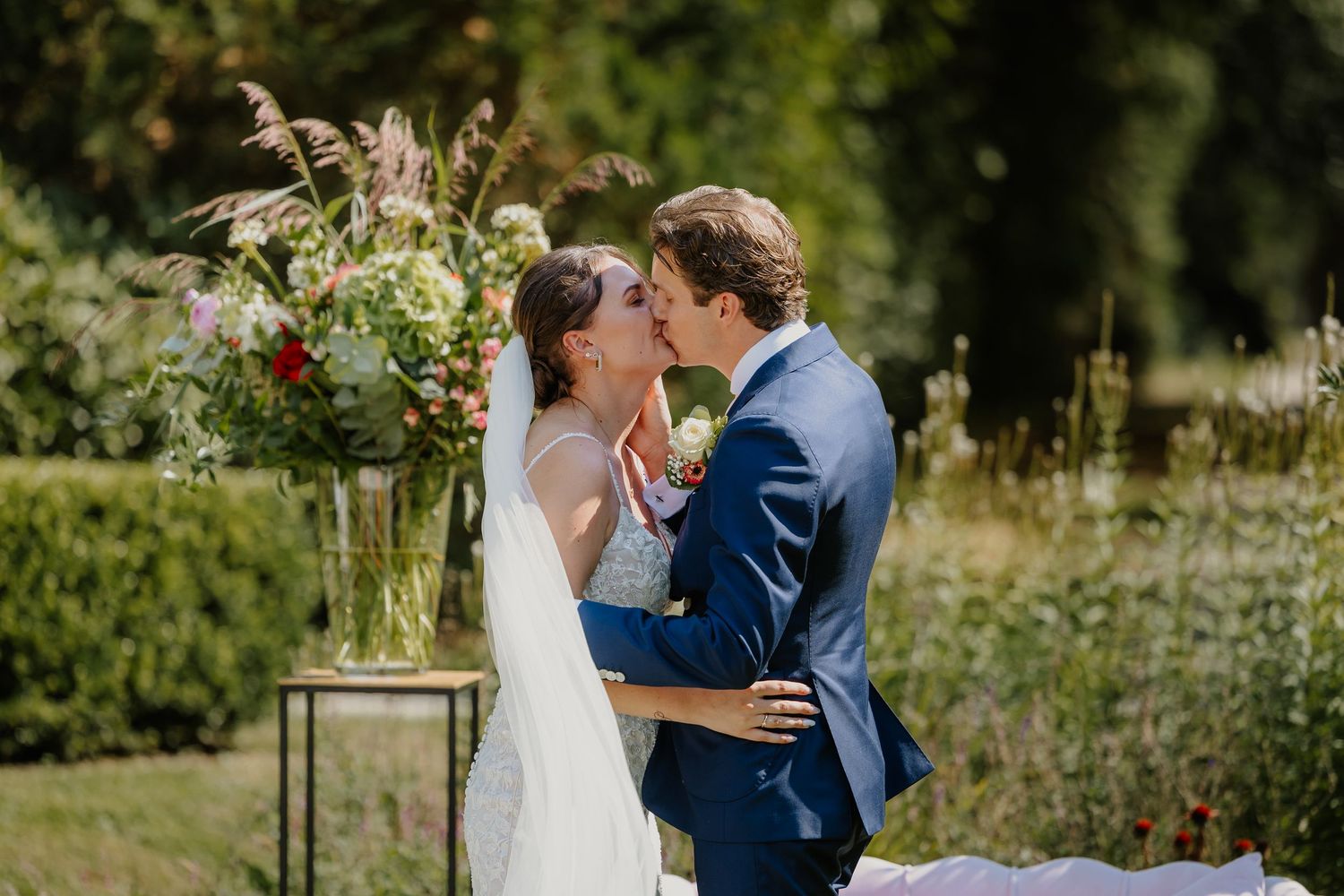 Bruidspaar kust elkaar tijdens hun ceremonie in een groene tuin