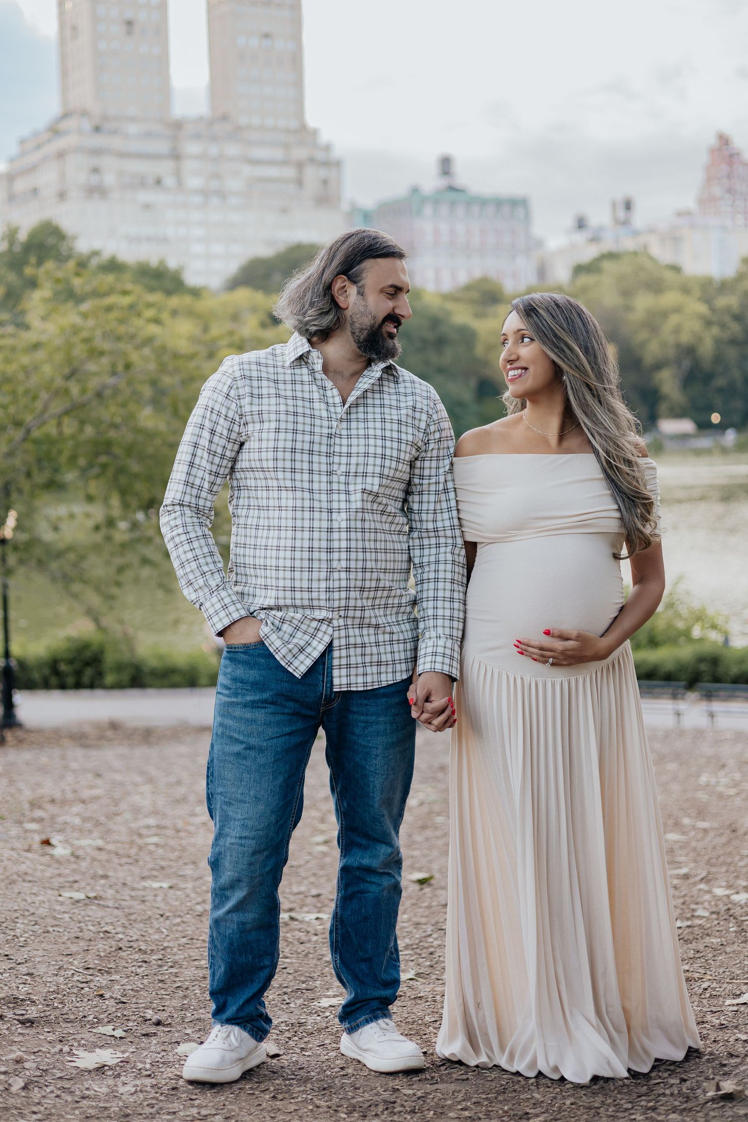 Happy couple holding hands during maternity photoshoot in Central Park, NYC.