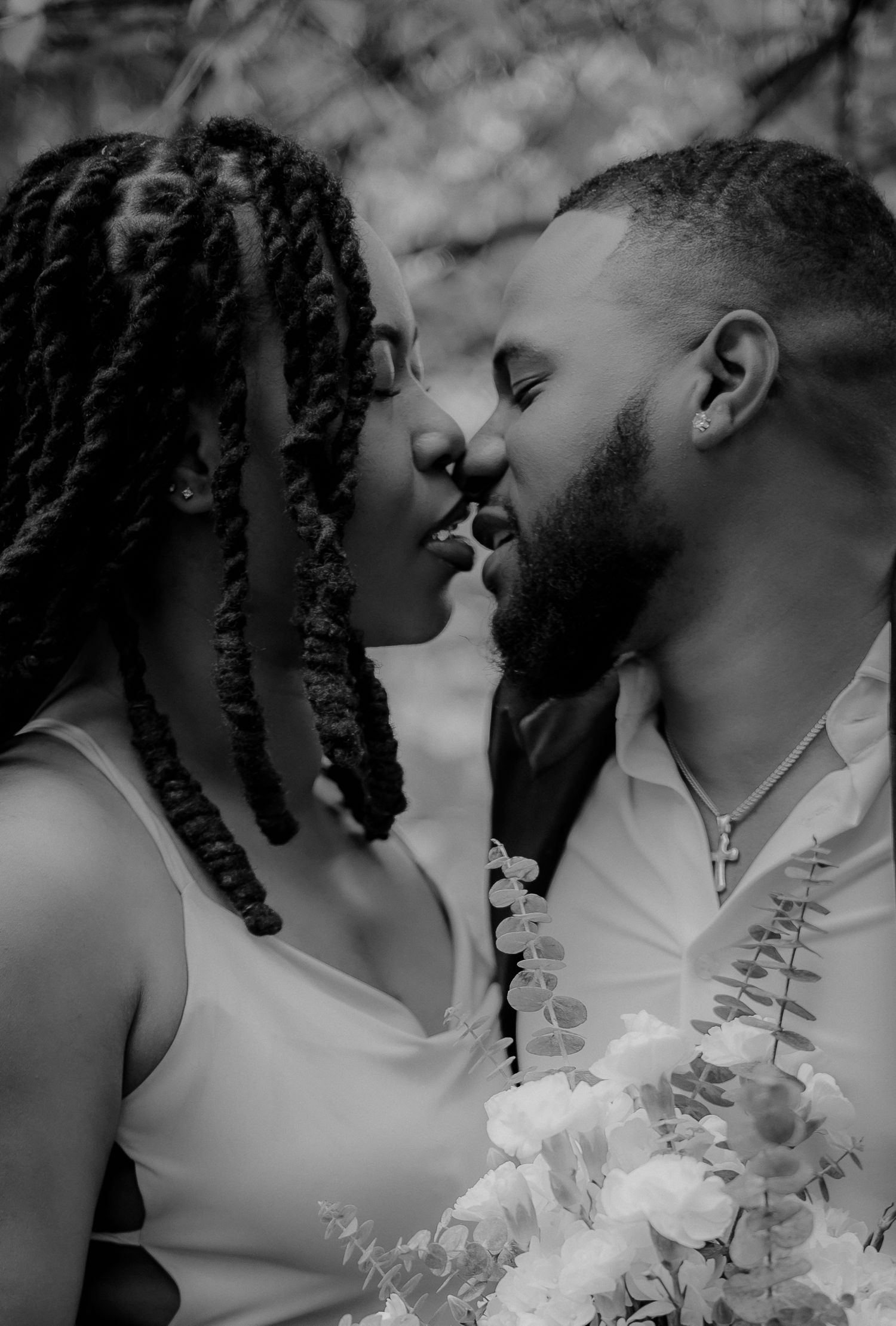 Black and white romantic close-up of couple about to kiss during outdoor engagement photo session.