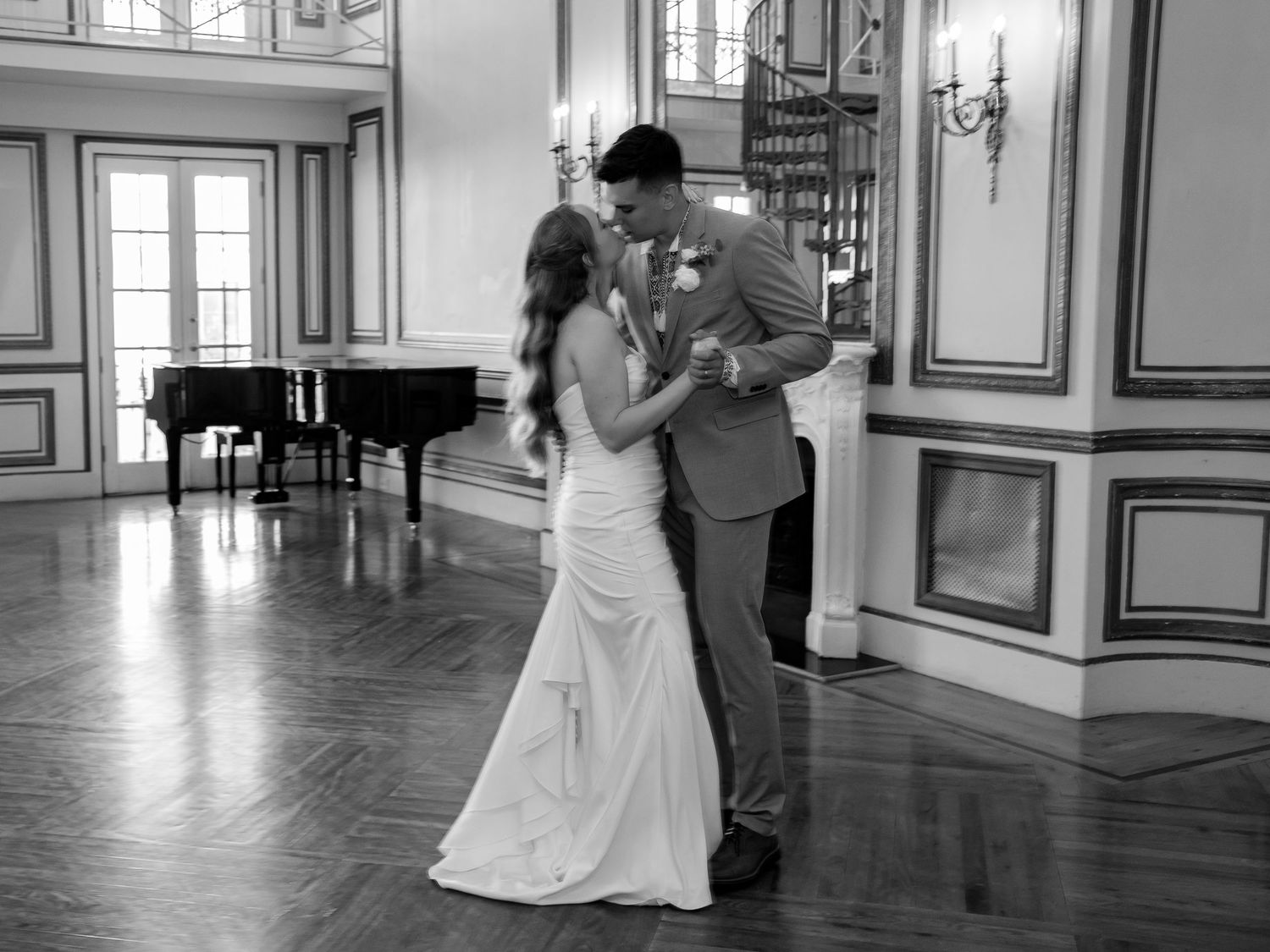 Black and white photo of bride and groom sharing their first dance in an elegant ballroom.