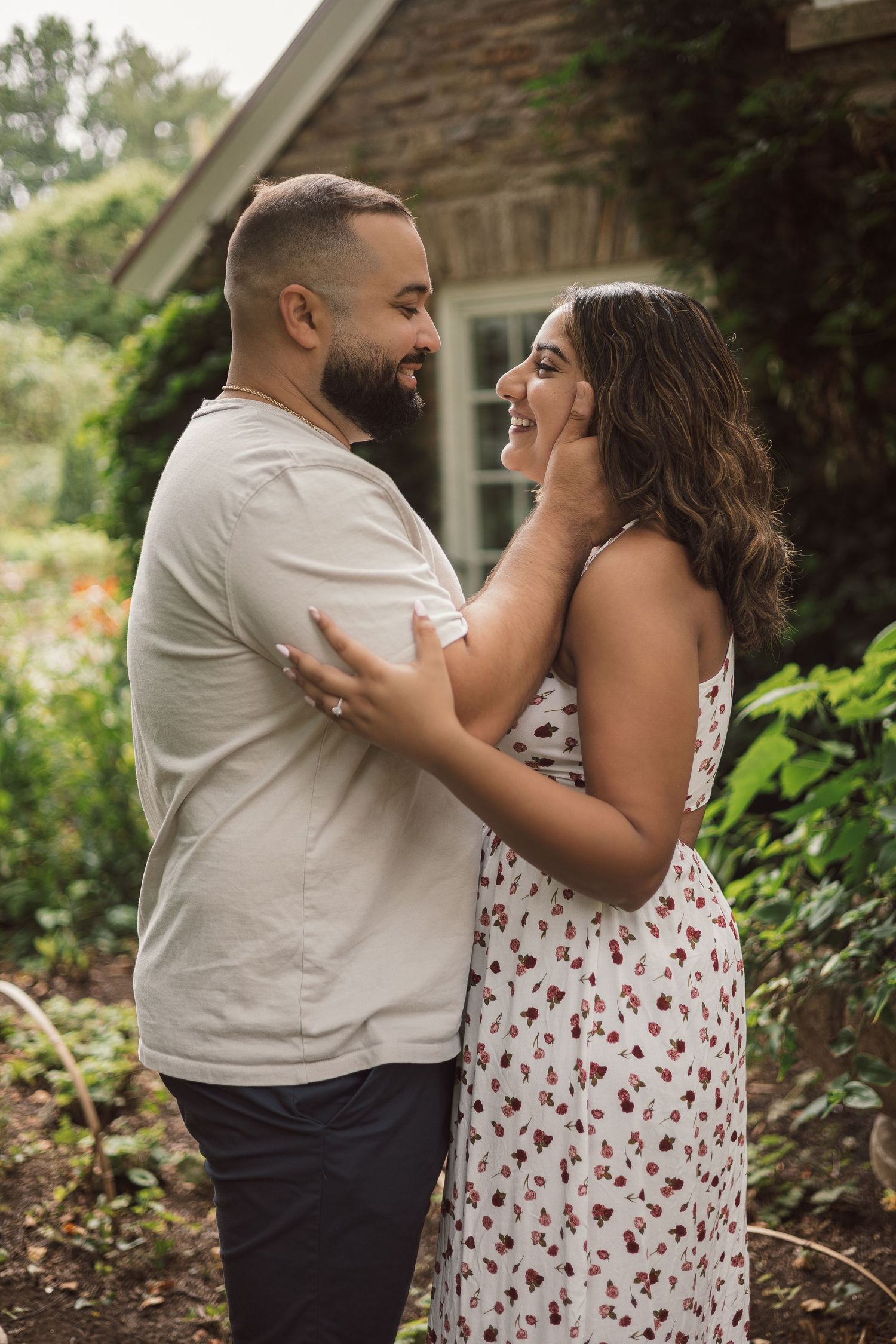 Joyful couple embracing and laughing together in a lush green garden setting.