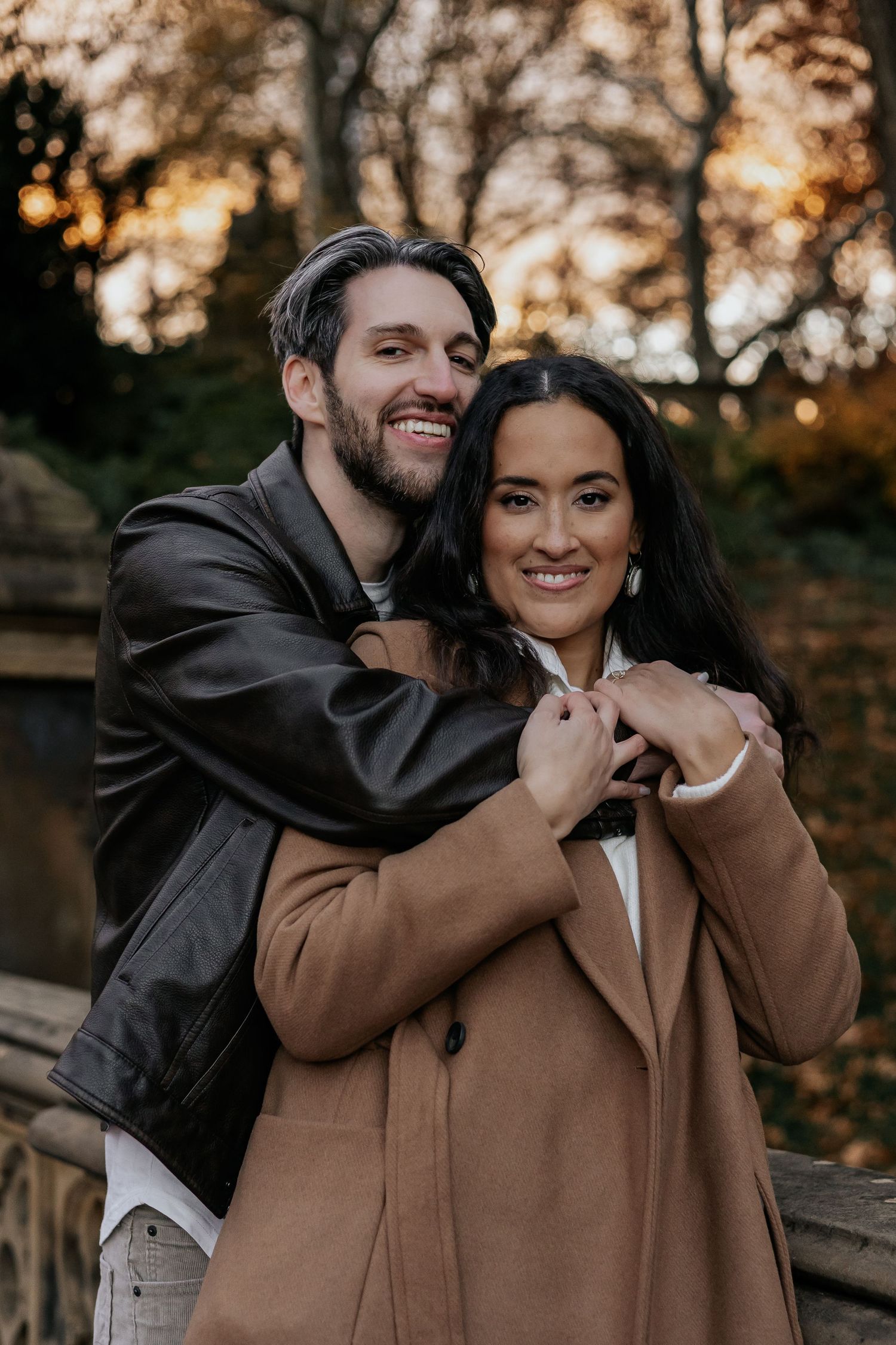 Smiling couple embracing warmly at Central Park during golden hour in autumn season.